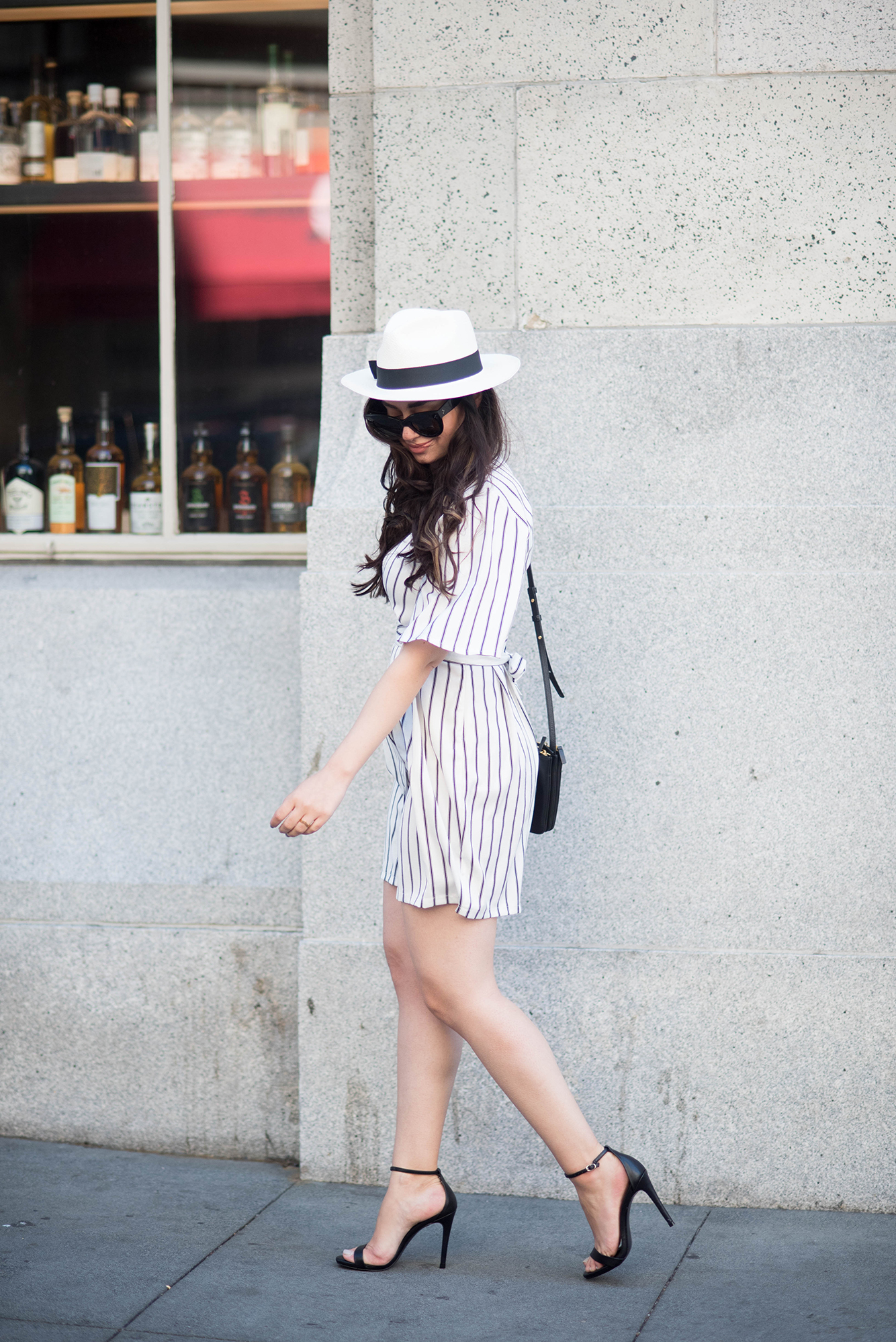 cee fardoe of coco & vera walks down the street in san francisco wearing a striped dress and panama hat