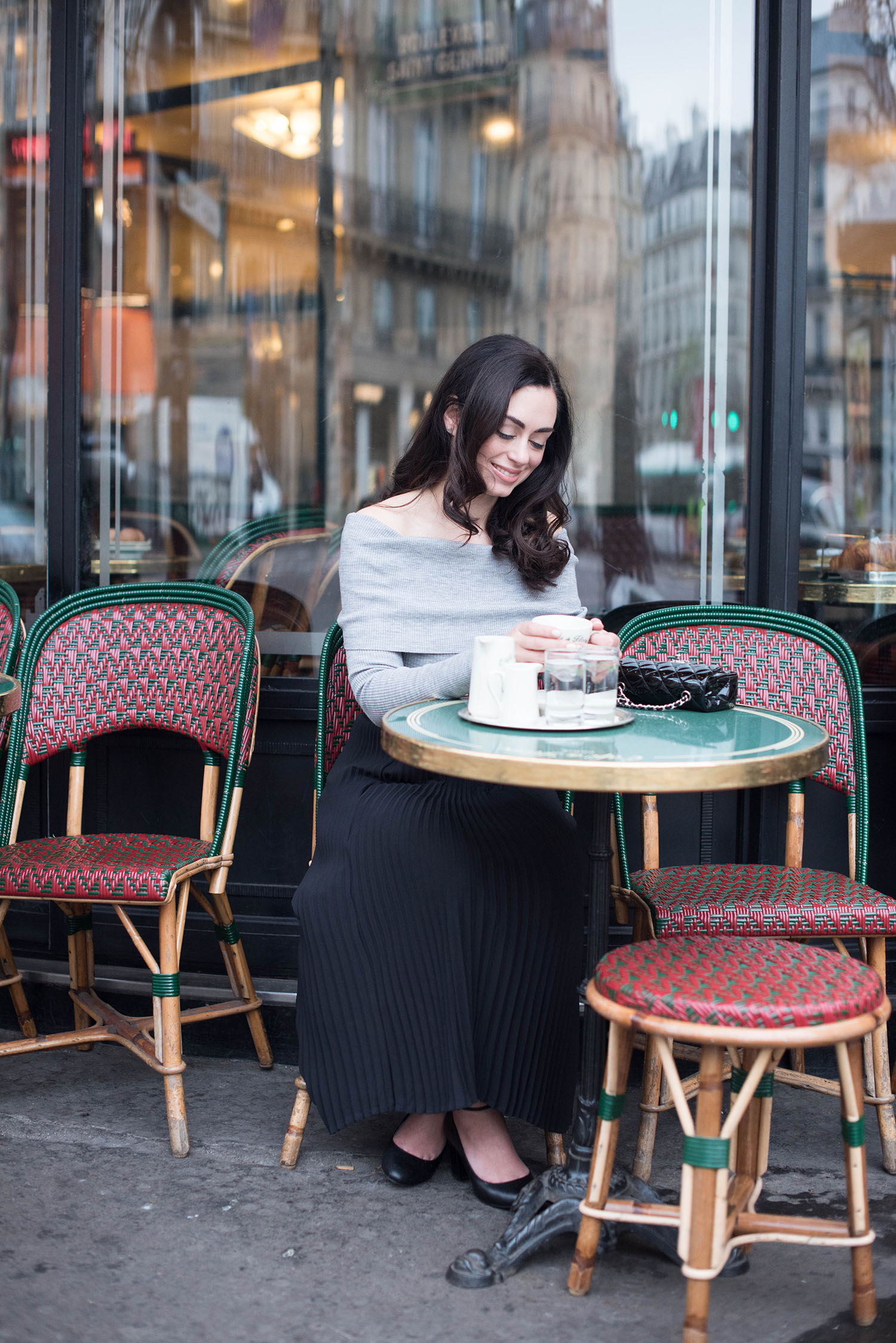Details of fashion blogger Cee Fardoe of Coco & Vera wearing an Aritzia off-shoulder sweater at the Cafe de Flore in Paris