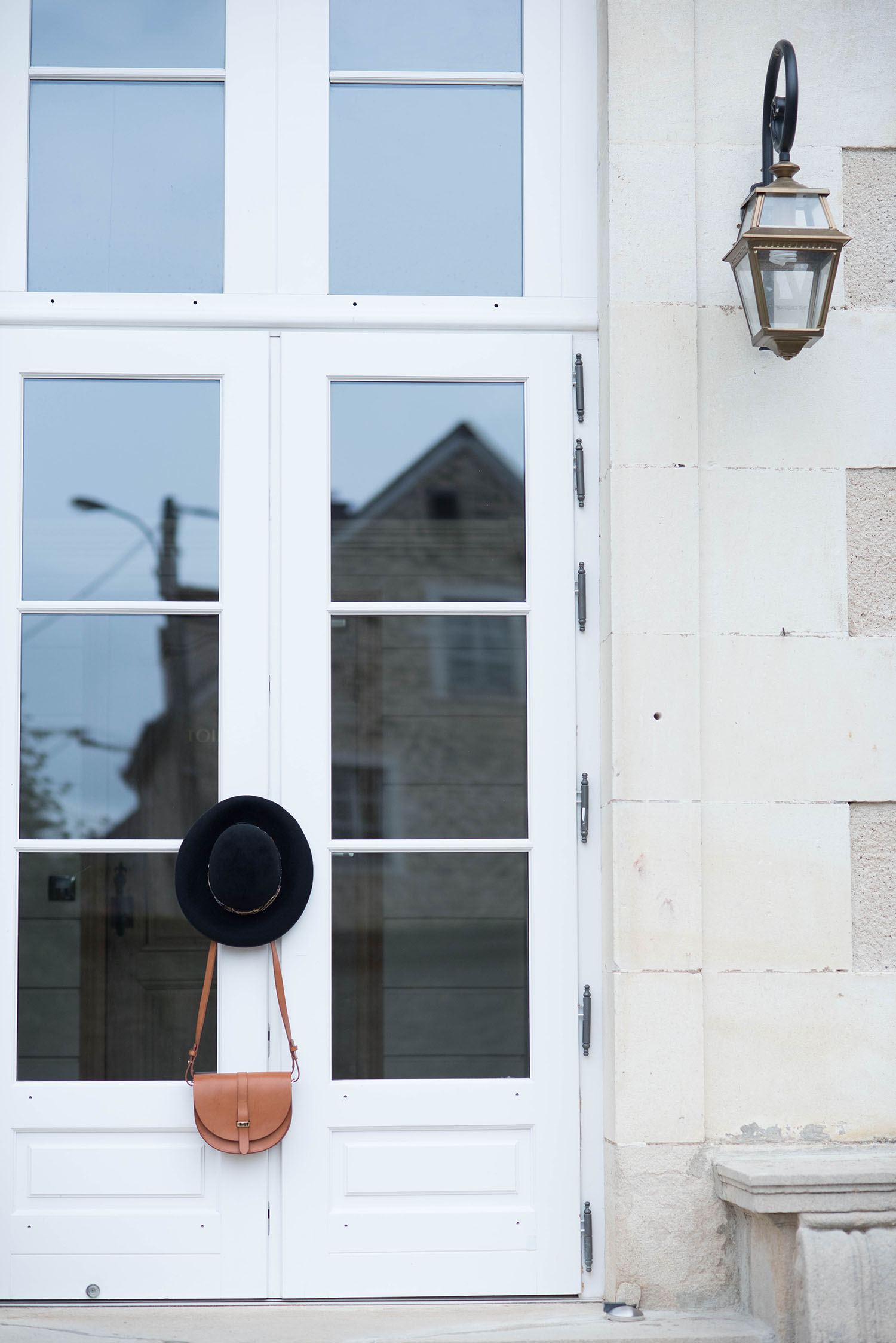 Krasnova Modiste black hat and Sezane Claude bag hanging on the door of Chateau Sainte-Sabine, shot by fashion blogger Cee Fardoe of Coco & Vera