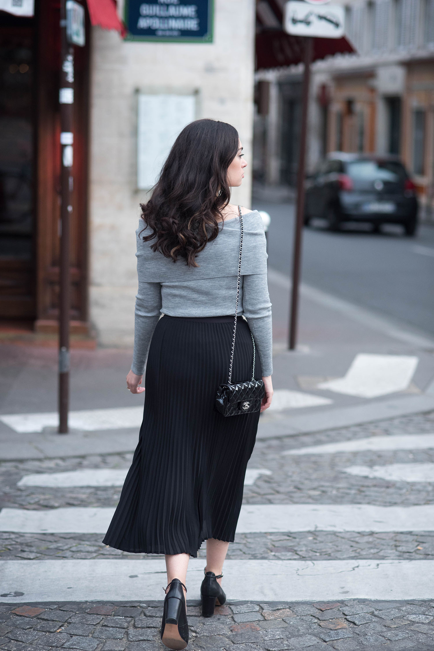 Fashion blogger Cee Fardoe of Coco & Vera walking in Paris wearing an Aritzia pleated skirt and Chanel handbag