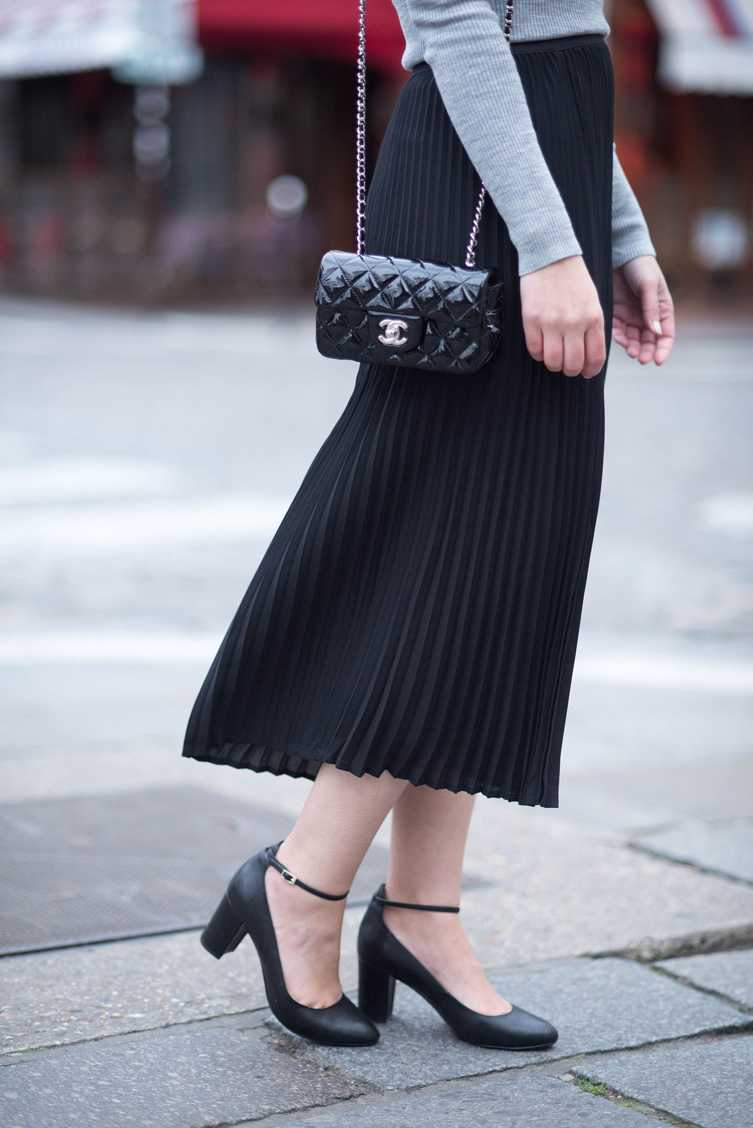 Outfit details on personal style blogger Cee Fardoe of Coco & Vera, wearing an Aritzia pleated skirt and Chanel handbag