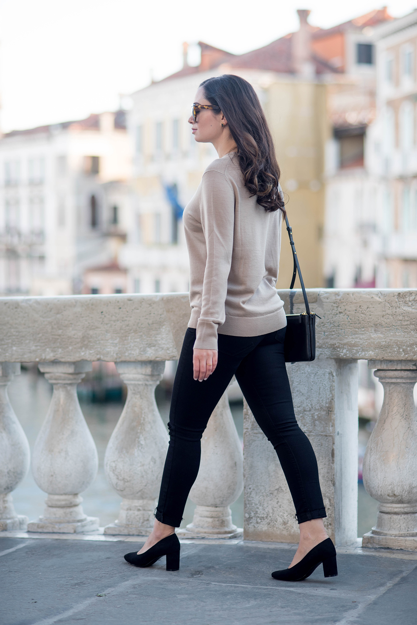 Fashion blogger Cee Fardoe of Coco & Vera walks on Rialto Bridge wearing a camel Uniqlo sweater