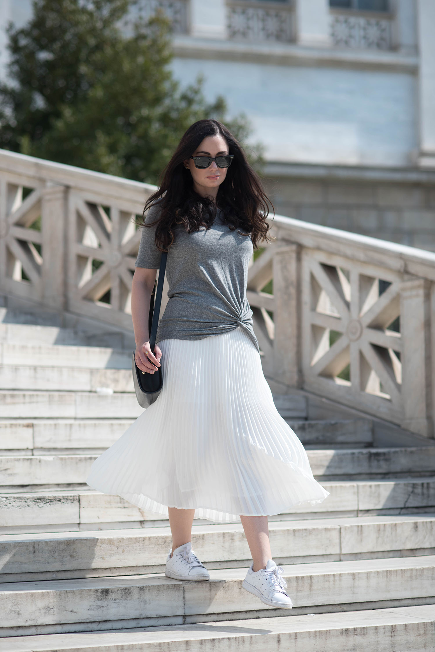 Fashion blogger Cee Fardoe of Coco & Vera walks down a marble staircase wearing a white pleated Aritzia skirt