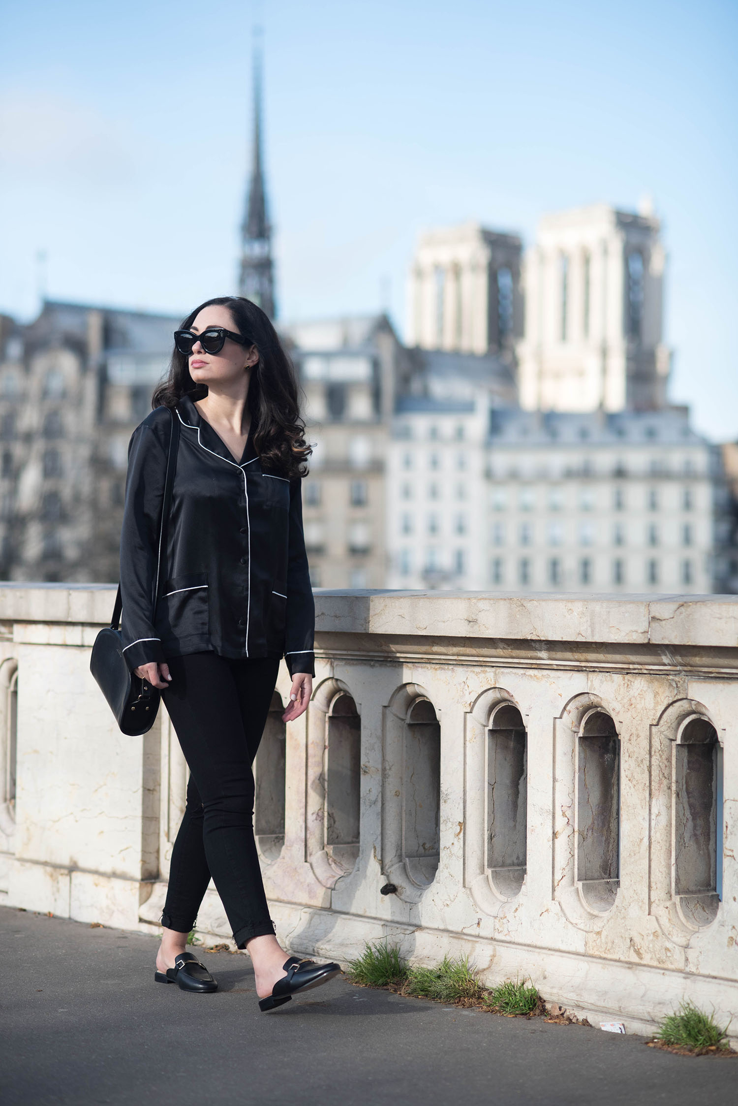 Fashion blogger Cee Fardoe of Coco & Vera walks on a Parisian bridge carrying an APC halfmoon bag