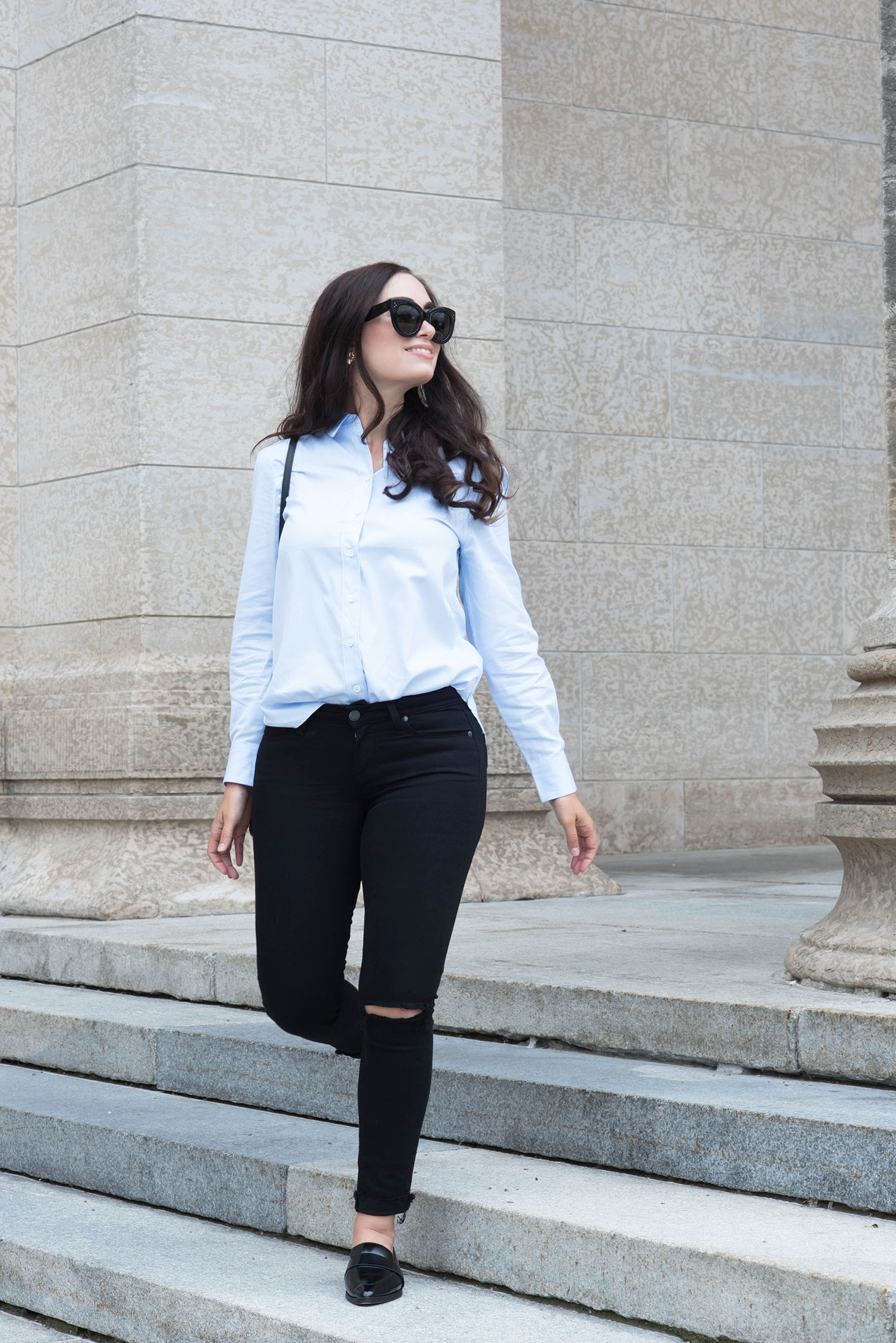 Canadian fashion blogger Cee Fardoe of Coco & Vera walks down a flight of stairs wearing an Equipment cotton blouse and Paige Denim jeans