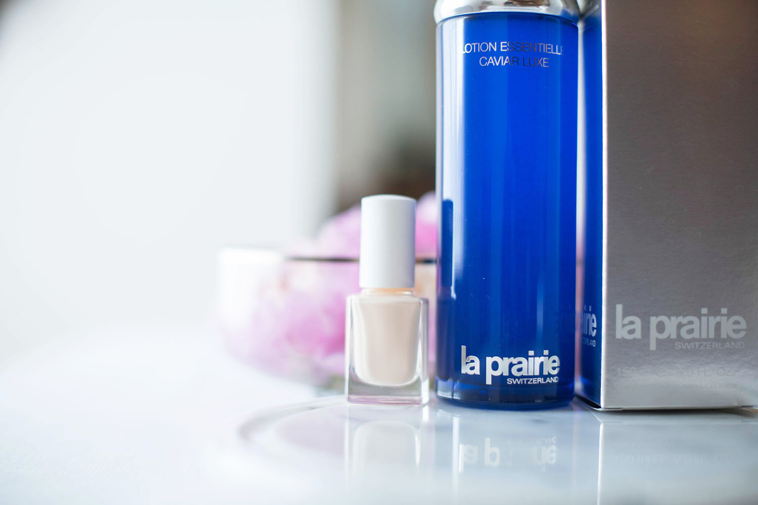 La Prairie skin caviar essence in lotion next to a bottle of nude nail polish, photographed by beauty blogger Cee Fardoe of Coco & Vera