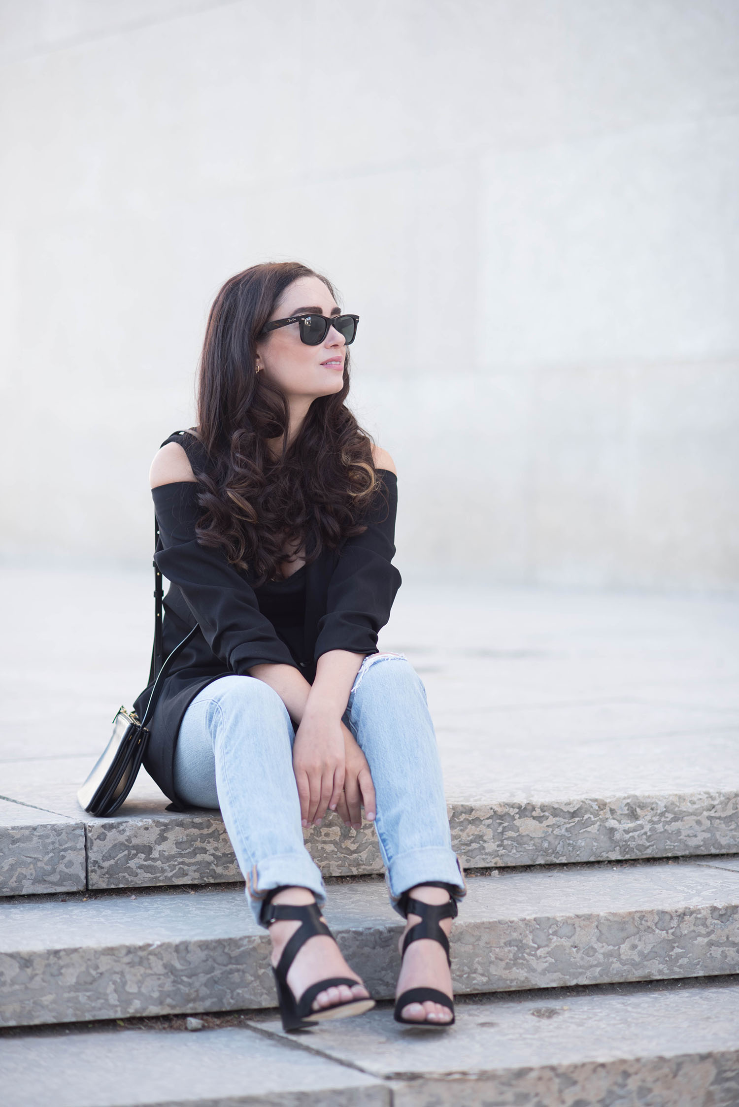 Fashion blogger Cee Fardoe of Coco & Vera sits on the stairs wearing an Ever New cold shoulder coat and Levis jeans