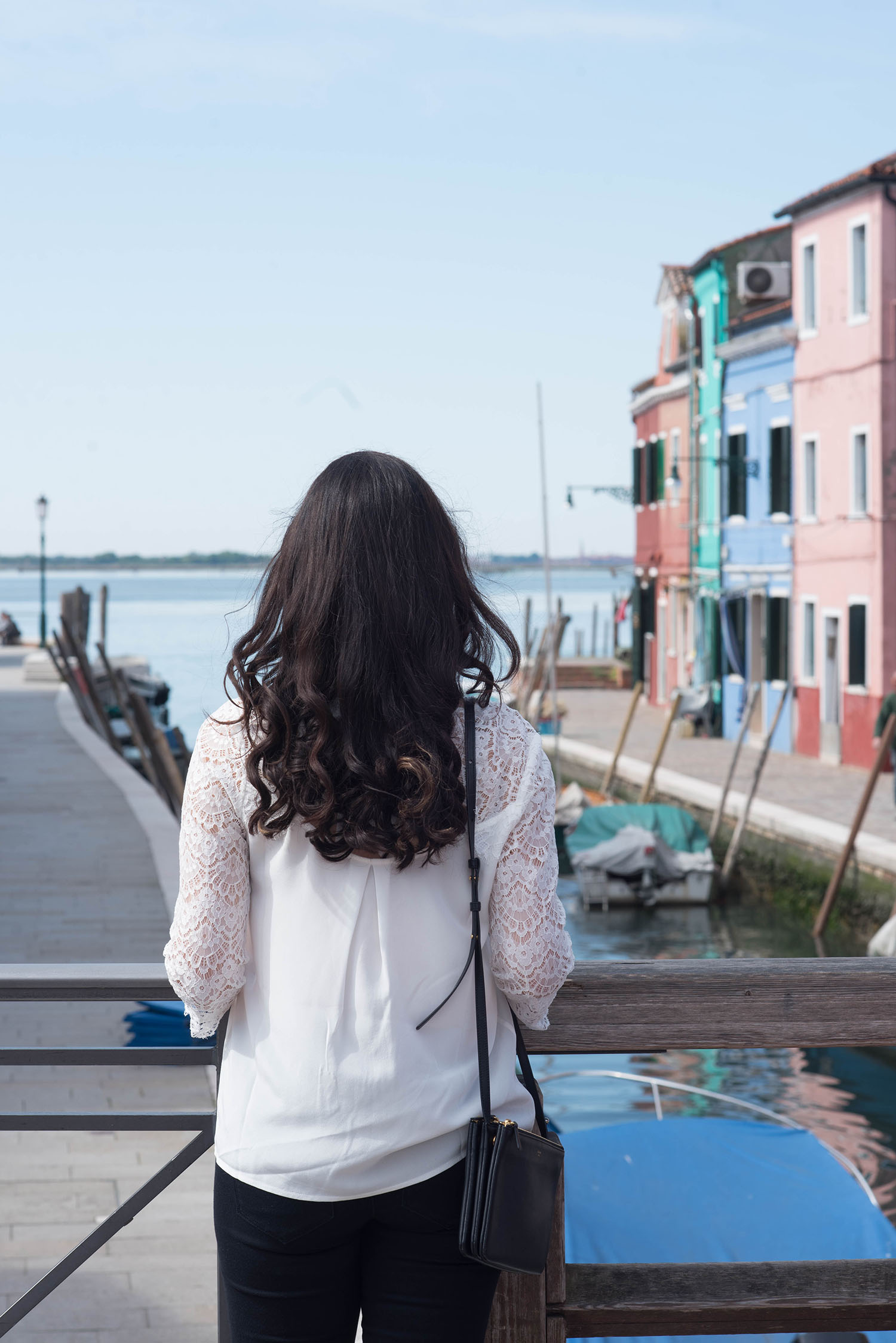 Top style blogger Cee Fardoe of Coco & Vera looks out over the sea on Burano wearing a white Sezane blouse