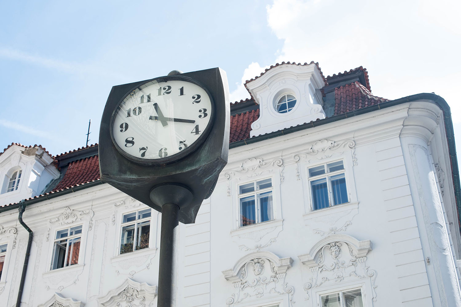 A white building and vintage clock in Prague, captured by travel blogger Cee Fardoe of Coco & Vera