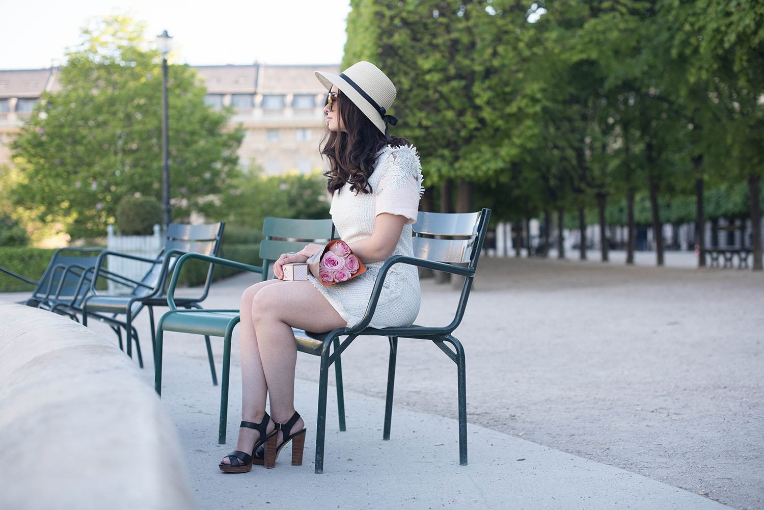 Canadian fashion blogger Cee Fardoe of Coco & Vera sits in the Palais Royal garden wearing a Floriane Fosso dress and Le Chateau sandals