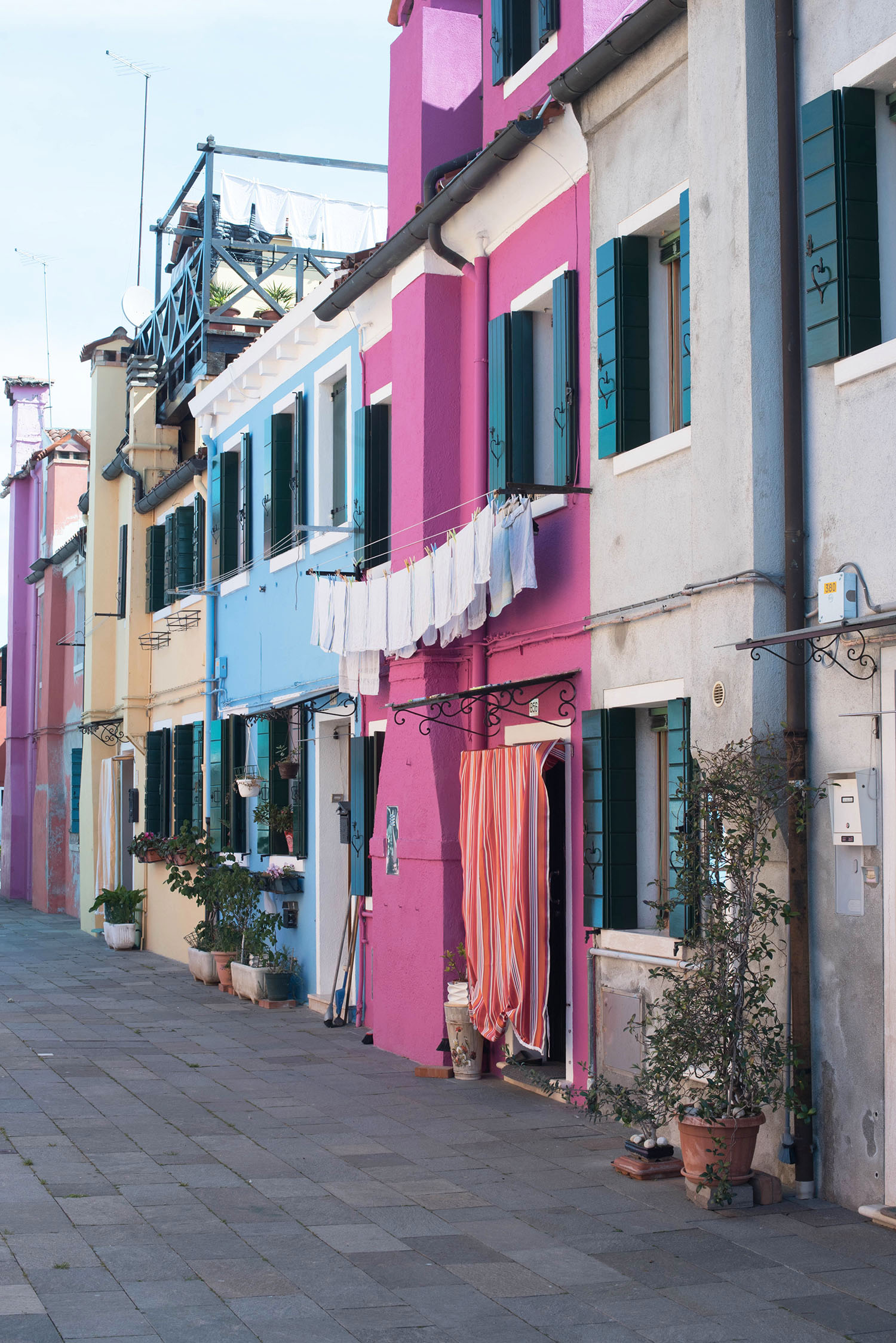 Pink and blue houses in a narrow laneway on Burano, Italy, captured by travel blogger Cee Fardoe of Coco & Vera