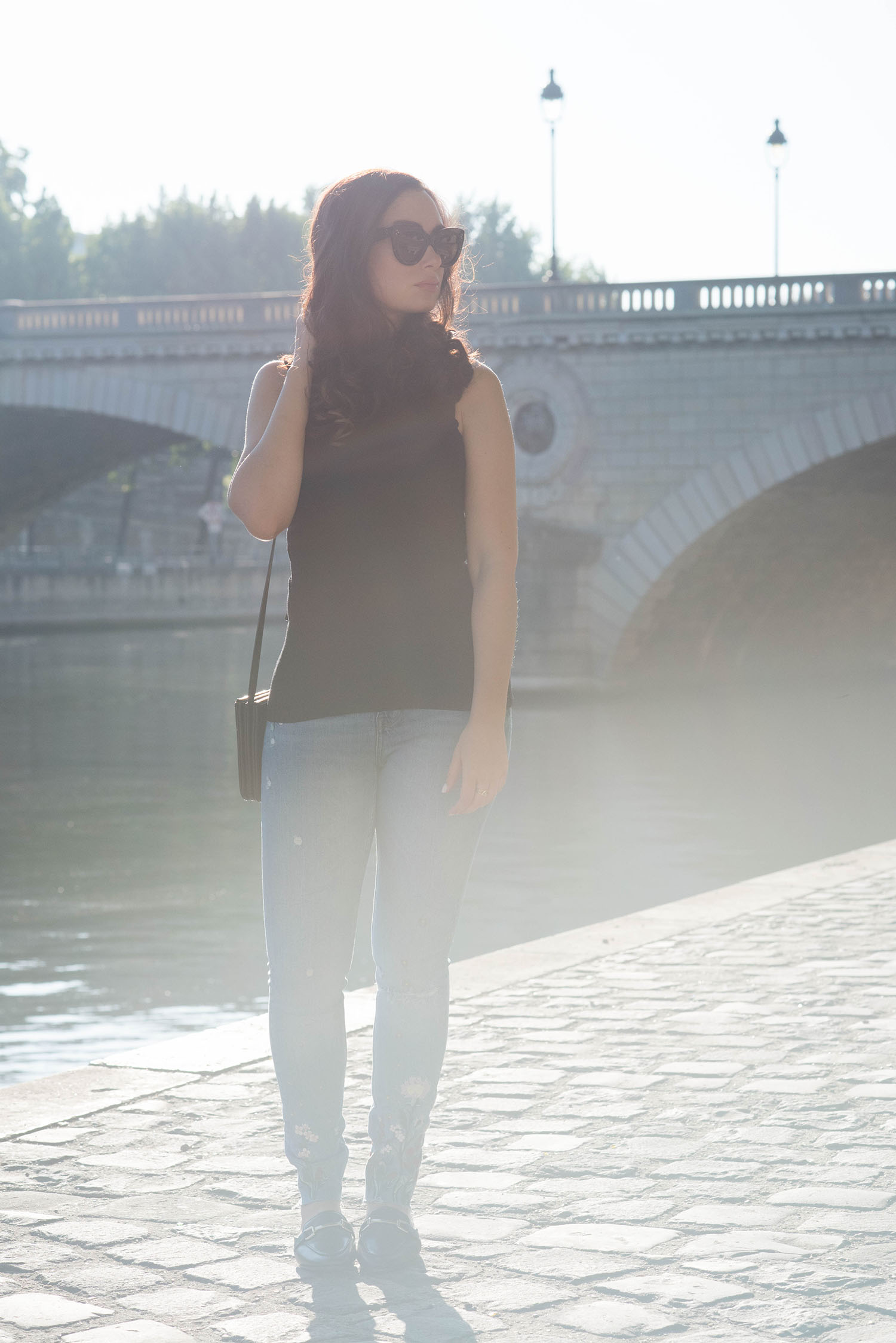Fashion blogger Cee Fardoe of Coco & Vera stands on Ile Saint-Louis in Paris wearing Zara embroidered jeans, Celine sunglasses and a Le Chateau top
