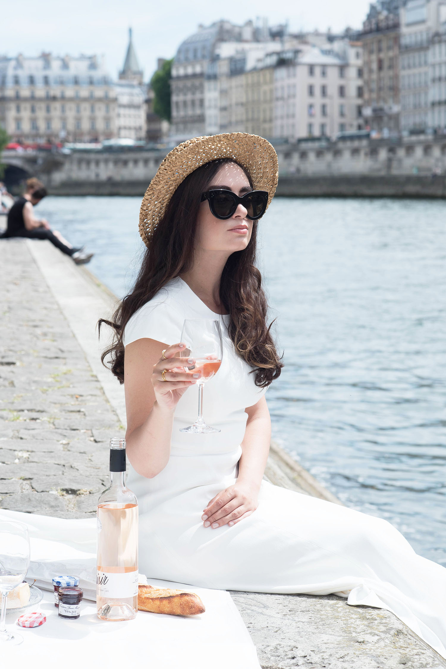 Style blogger Cee Fardoe of Coco & Vera sits on the banks of the Seine river in Paris wearing an Ivy & Oak white dress