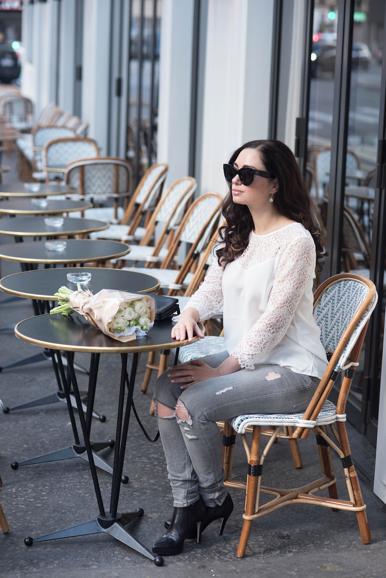 Fashion blogger Cee Fardoe of Coco & Vera sits at cafe Maison Marie in Paris wearing a white silk and lace Sezane blouse