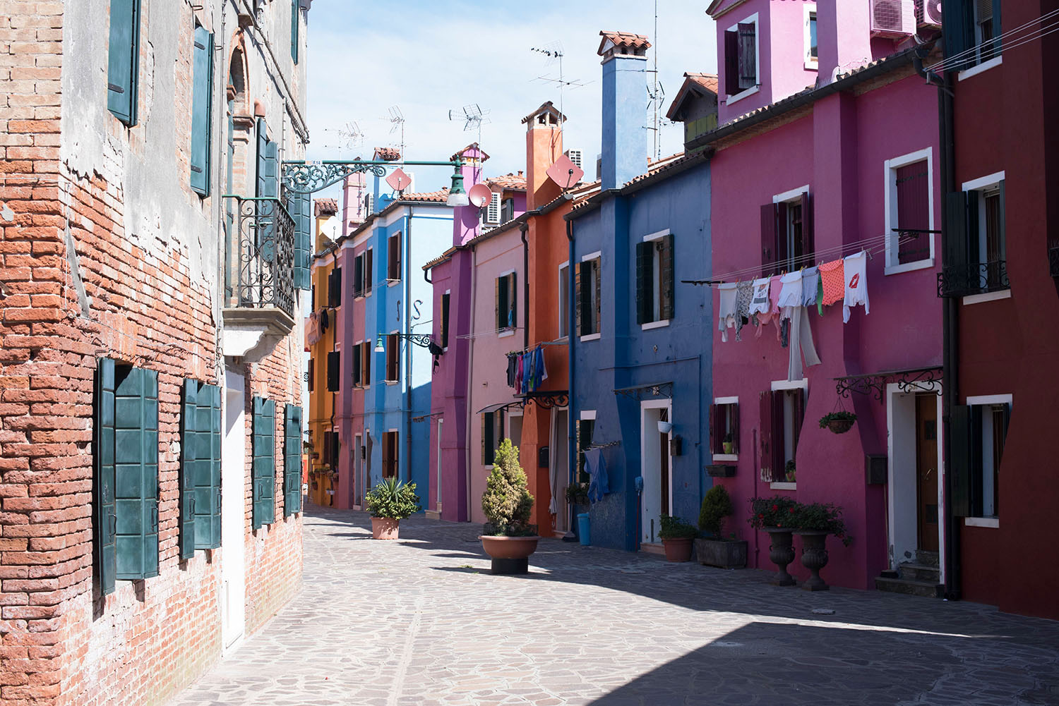 A narrow lane of brightly coloured houses on Burano, Italy, as captured by travel blogger Cee Fardoe of Coco & Vera