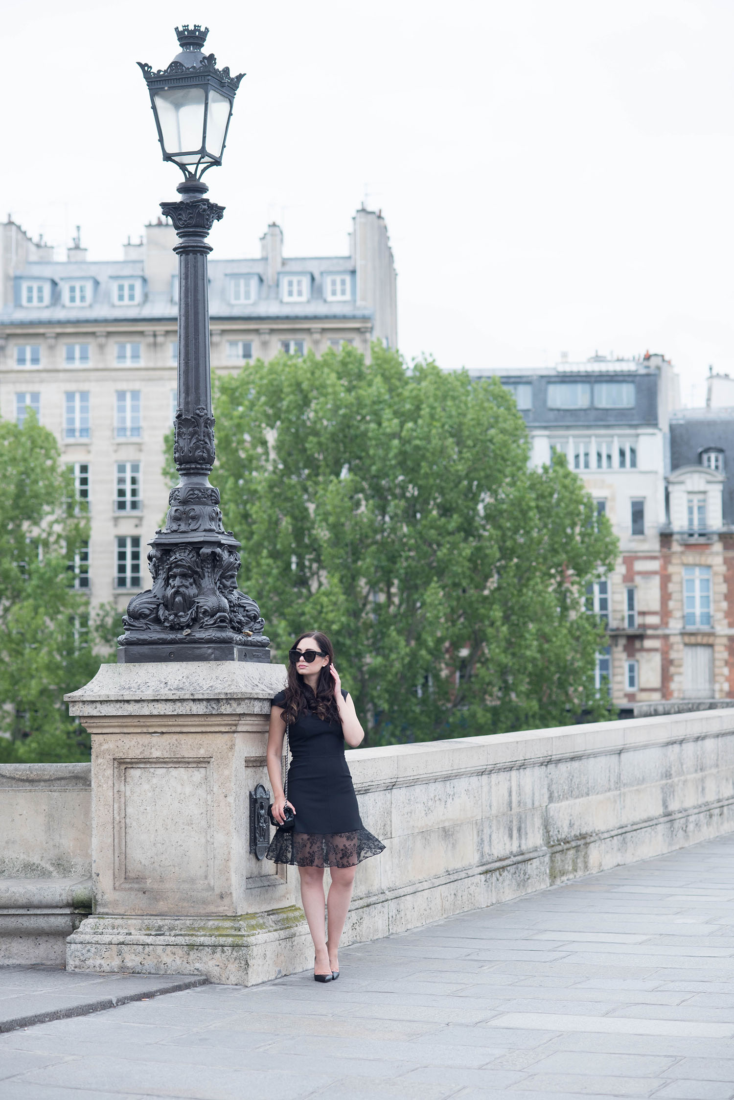 Canadian fashion blogger stands on Pont-Neuf in Paris wearing a Carven dress and carrying a Chanel extra mini handbag
