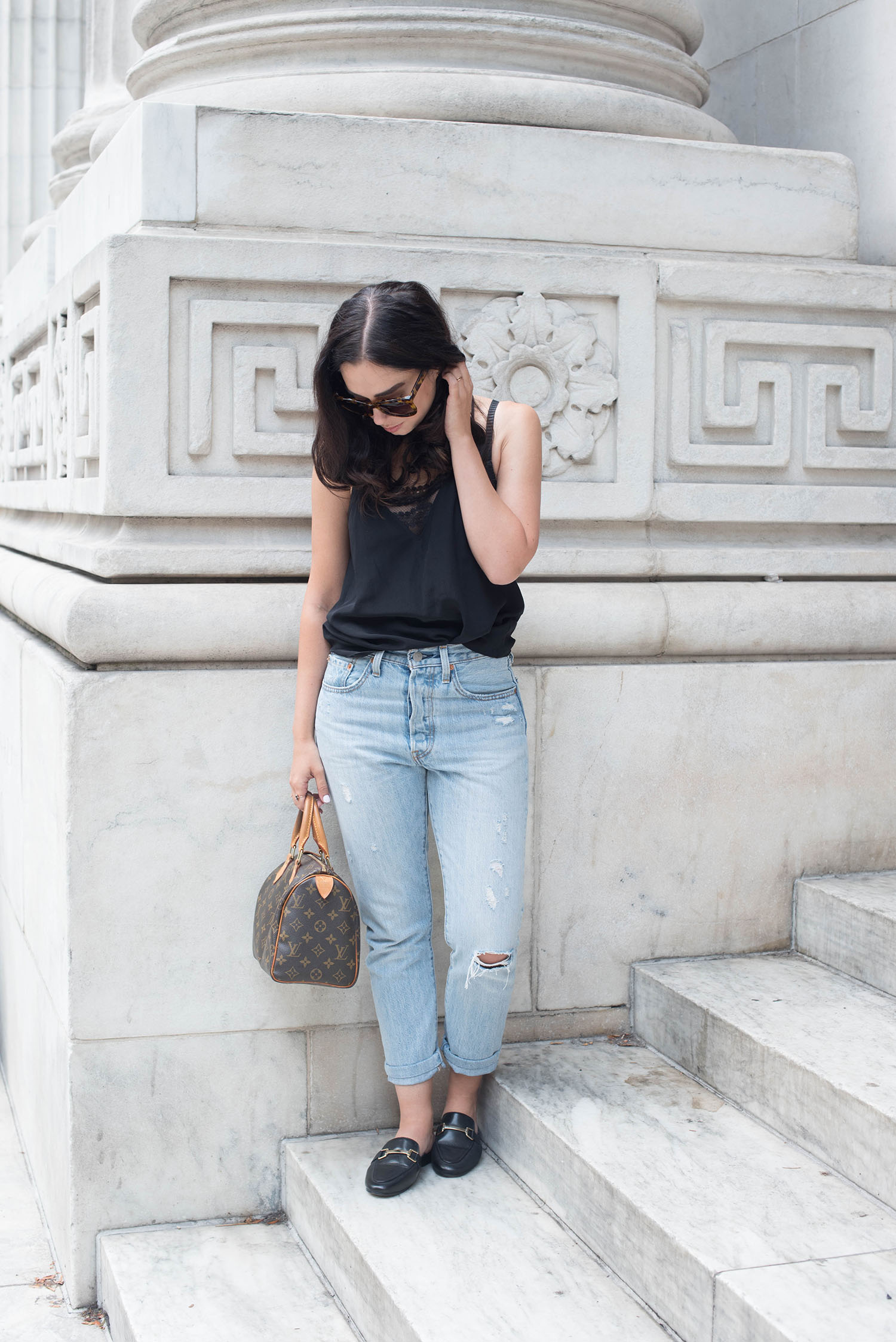 Winnipeg fashion blogger Cee Fardoe of Coco & Vera stands on the stairs of the Carnegie Library in Manhattan, wearing Levi's jeans and carrying a Louis Vuitton Speedy 25
