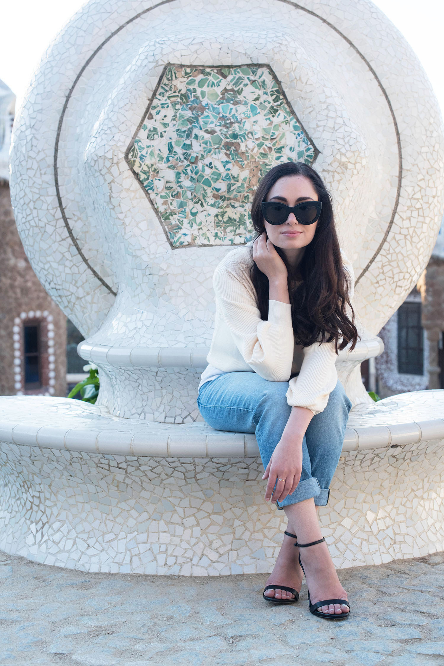 Style blogger Cee Fardoe of Coco & Vera sits on a tile bench at Parc Guell wearing Celine Audrey sunglasses and Zara jeans