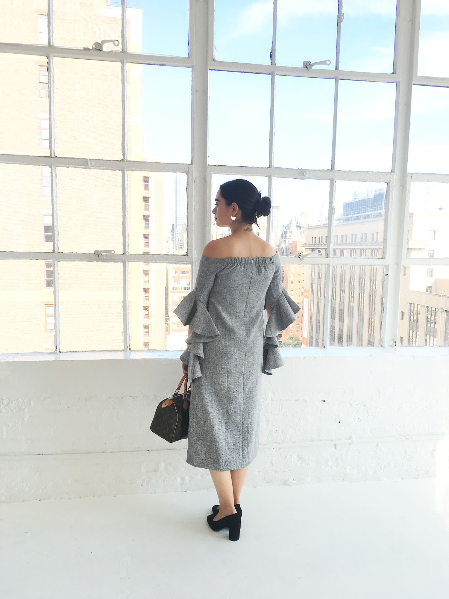 Fashion blogger Cee Fardoe of Coco & Vera wears a Metisu grey statement sleeve dress in an all white loft in New York