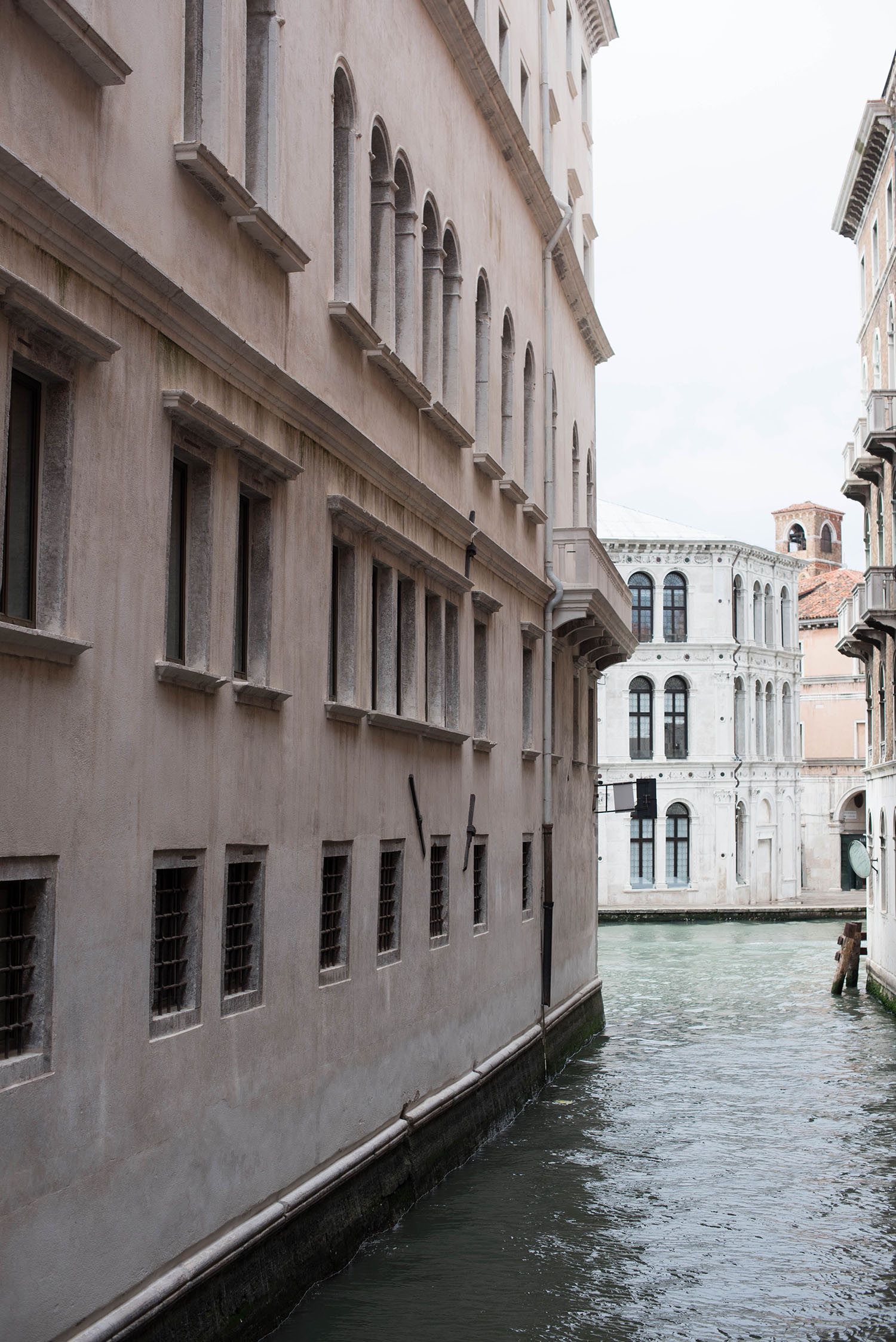 A quiet canal in Venice with a white building at the end, as captured by Paris travel blogger Cee Fardoe of Coco & Vera