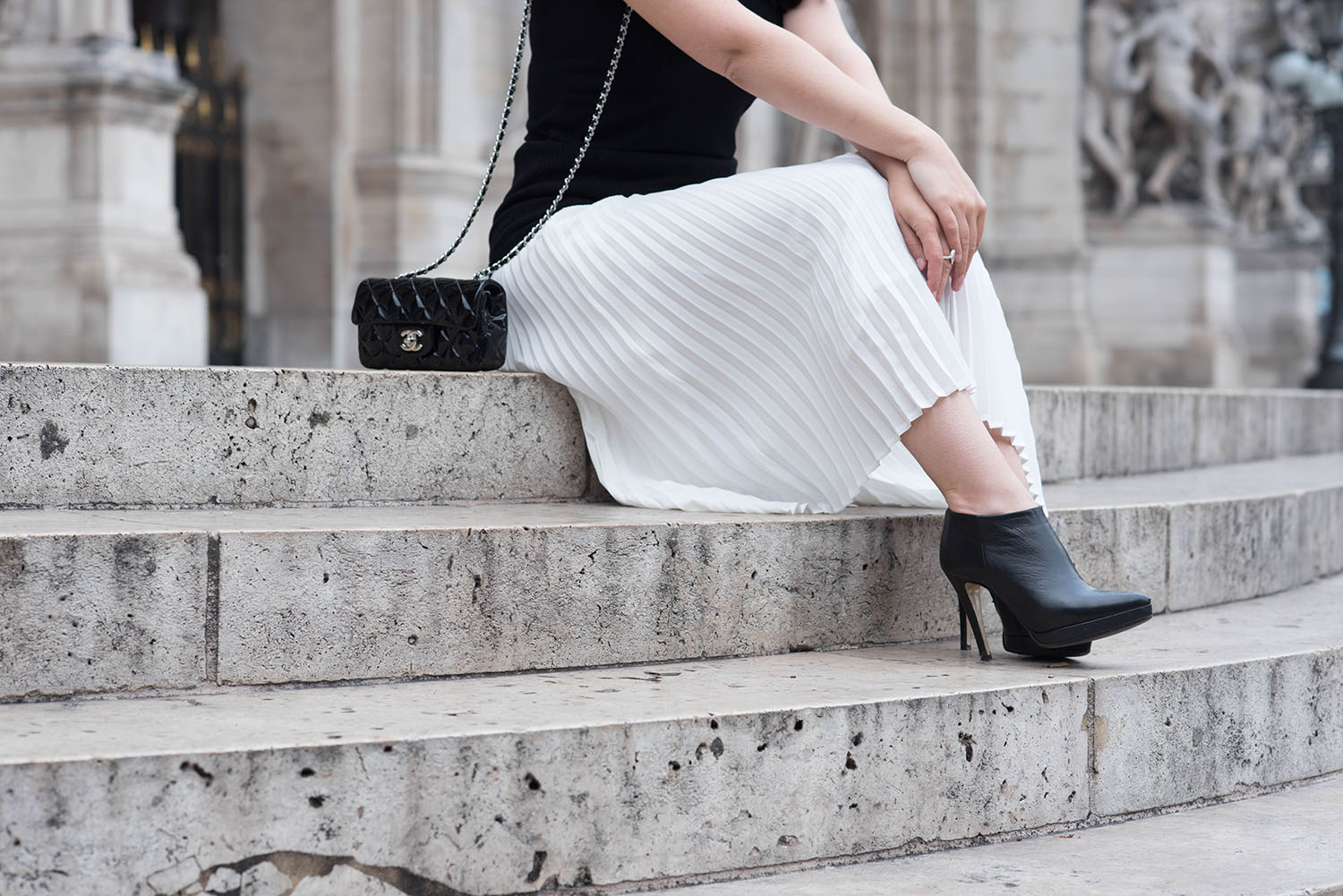 Outfit details on fashion blogger Cee Fardoe of Coco & Vera, including a Chanel extra mini patent handbag, Le Chateau ankle boots and Aritzia white pleated skirt