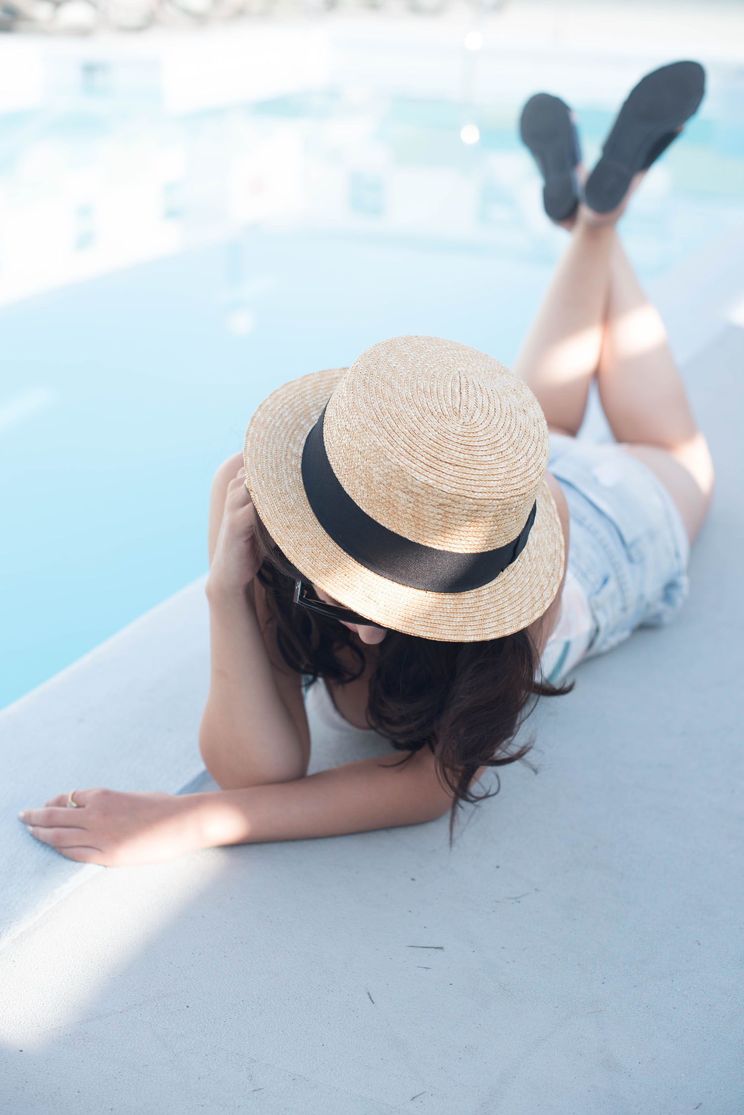 Winnipeg fashion blogger Cee Fardoe of Coco & Vera lays poolside wearing Aldo Cammila slides, One Teaspoon denim shorts and an Aritzia straw hat