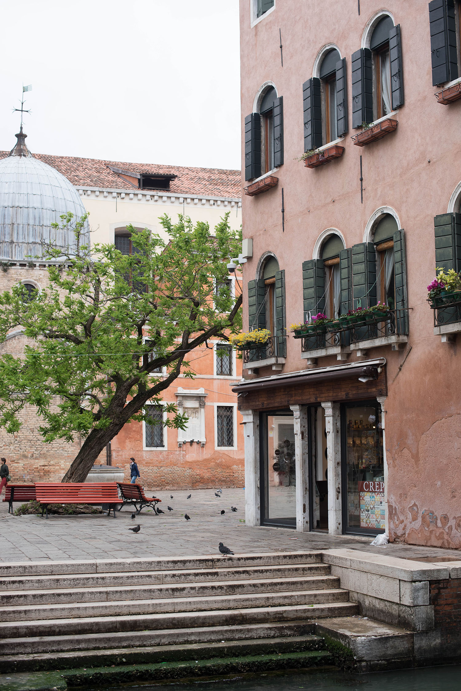 A typical square in Venice, featuring a pink apartment, a red bench and a tree, captured by top Winnipeg travel blogger Cee Fardoe of Coco & Vera