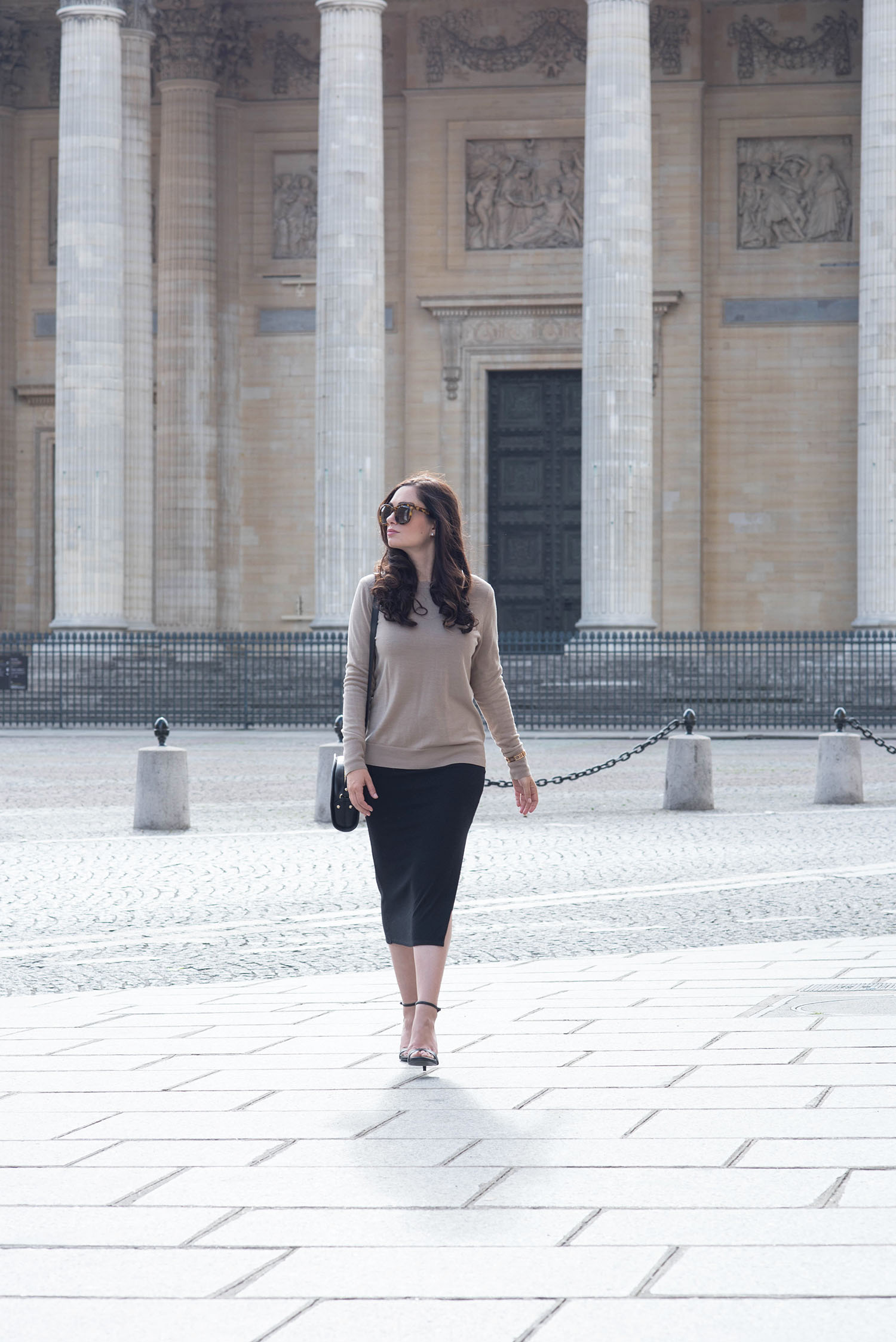 Canadian fashion blogger Cee Fardoe of Coco & Vera walks in front of the Pantheon in Paris wearing a Uniqlo camel sweater and Steve Madden Stecy sandals