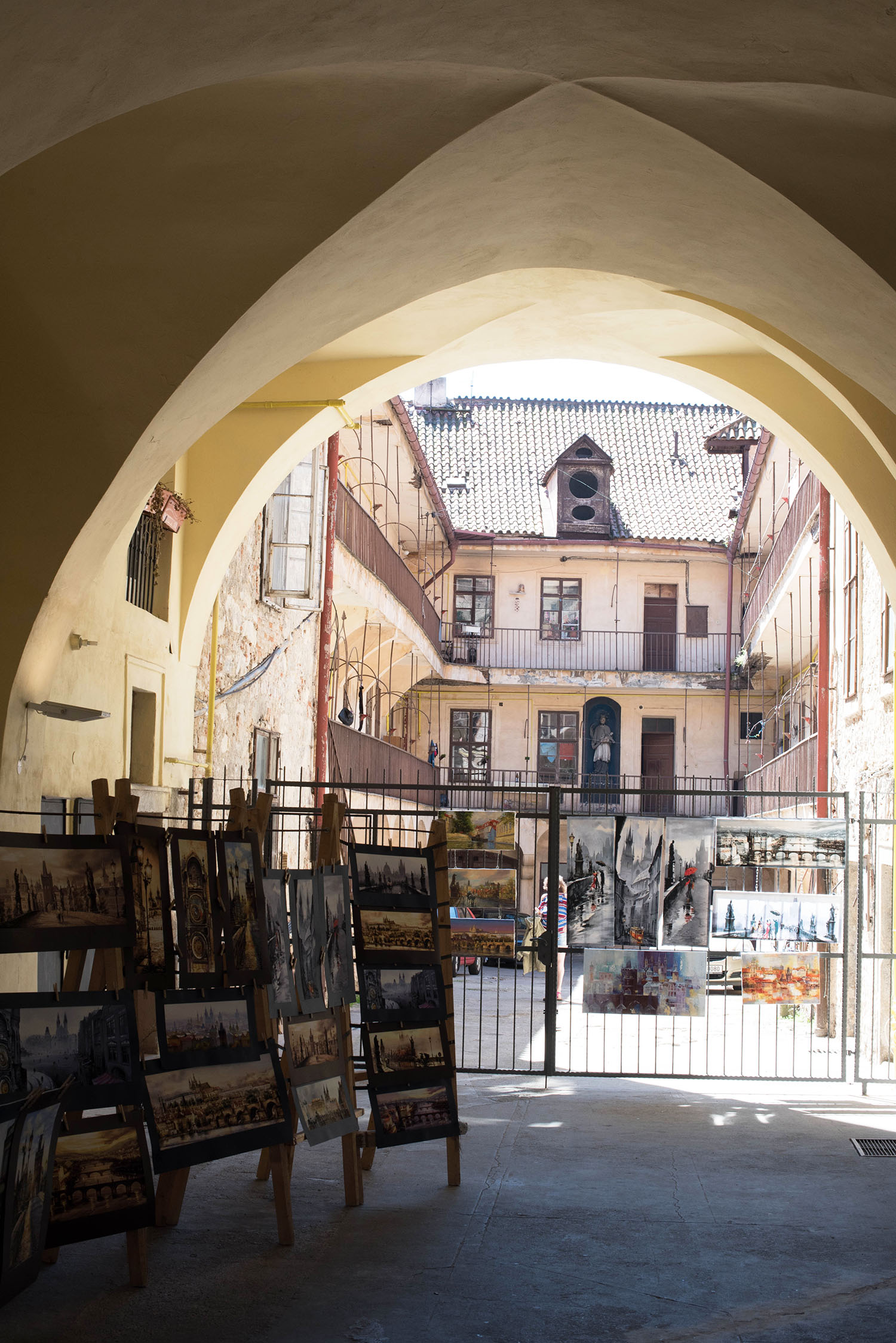 Paintings for sale under a medieval archway in Prague, as captured by travel blogger Cee Fardoe of Coco & Vera