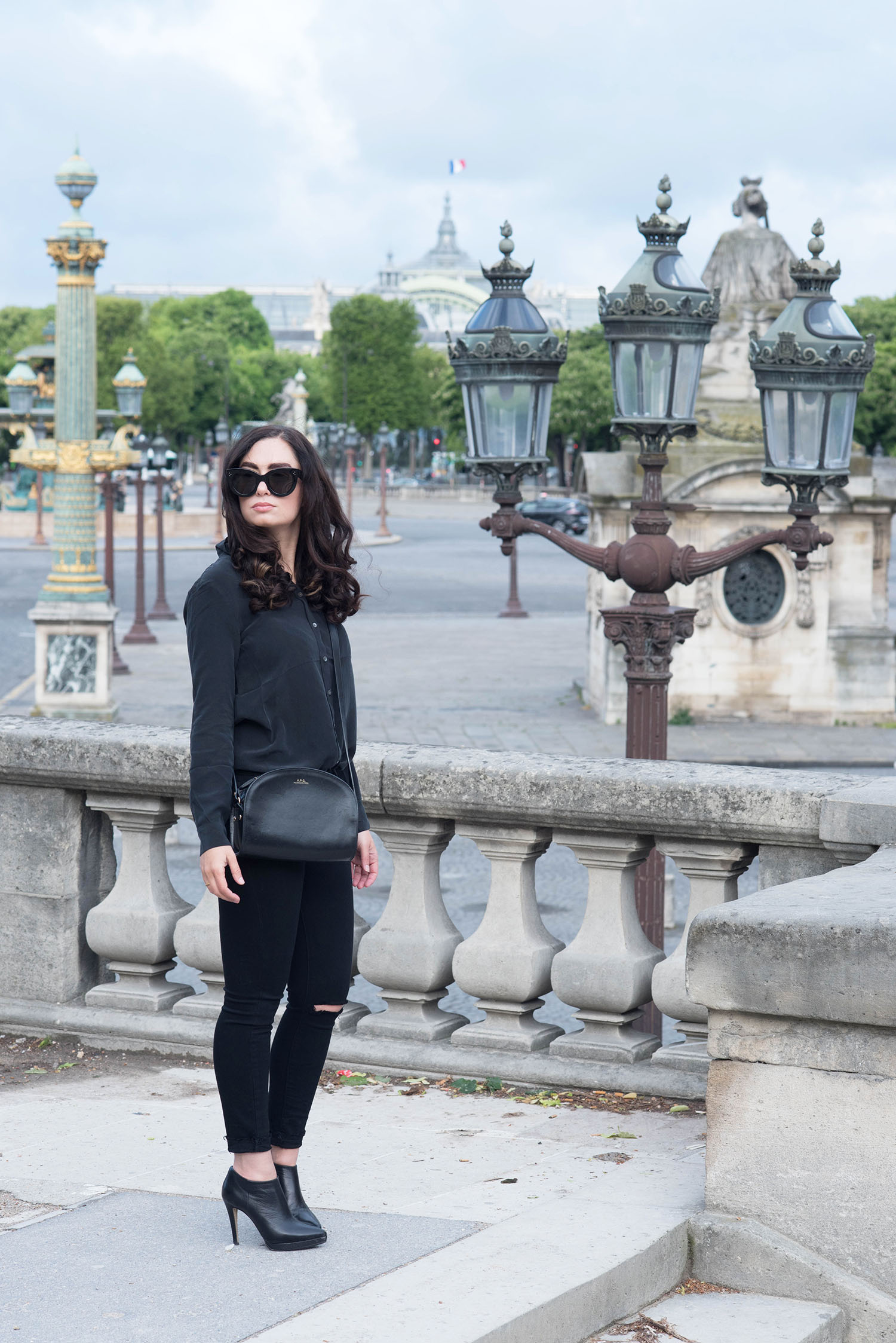 Fashion blogger Cee Fardoe of Coco & Vera stands at Place de la Concorde in Paris wearing an Everlane silk blouse and carrying an APF halfmoon bag