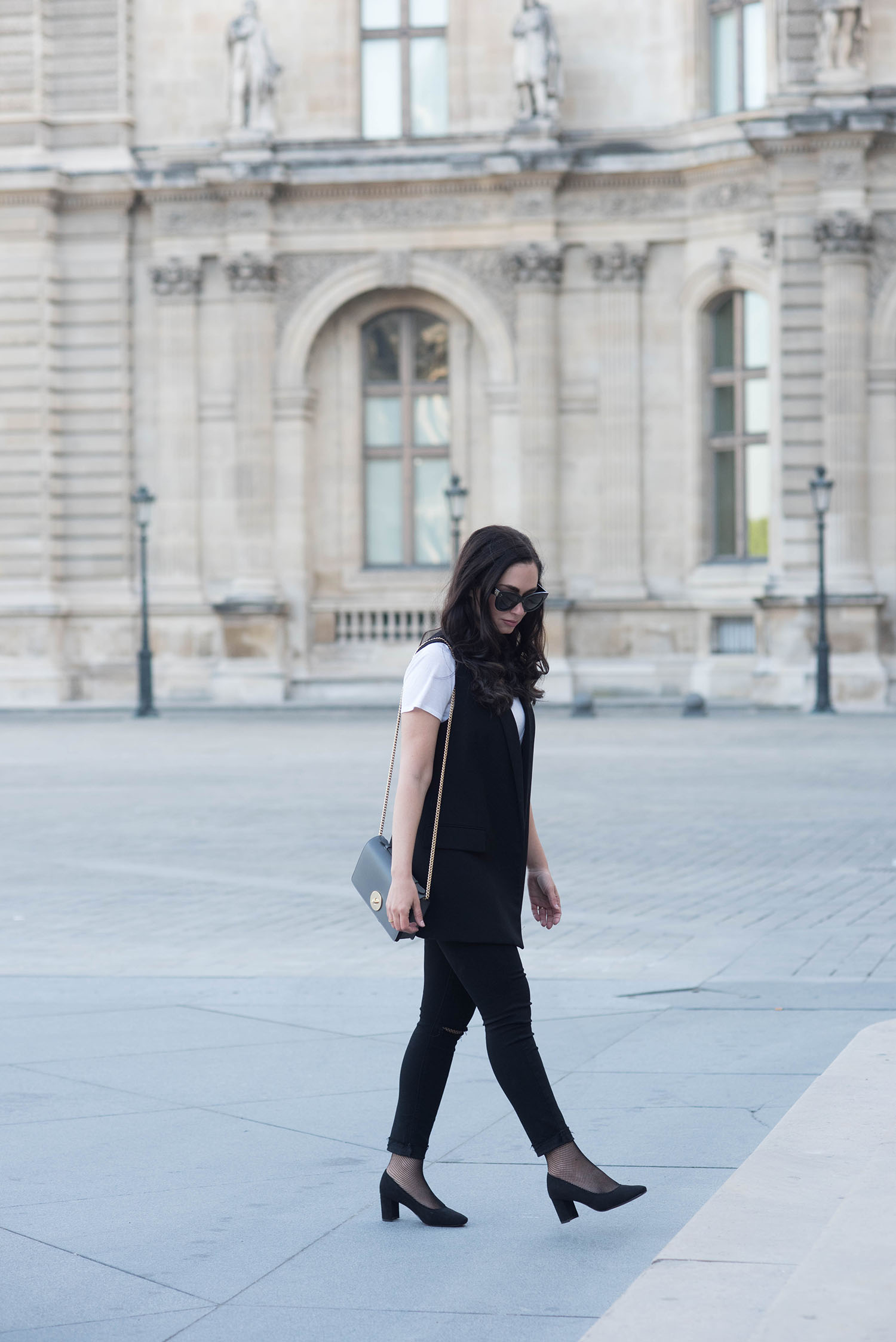 Winnipeg fashion blogger Cee Fardoe of Coco & Vera walks outside the Louvre museum in Paris wearing a black Zara waistcoat and Celine Audrey sunglasses