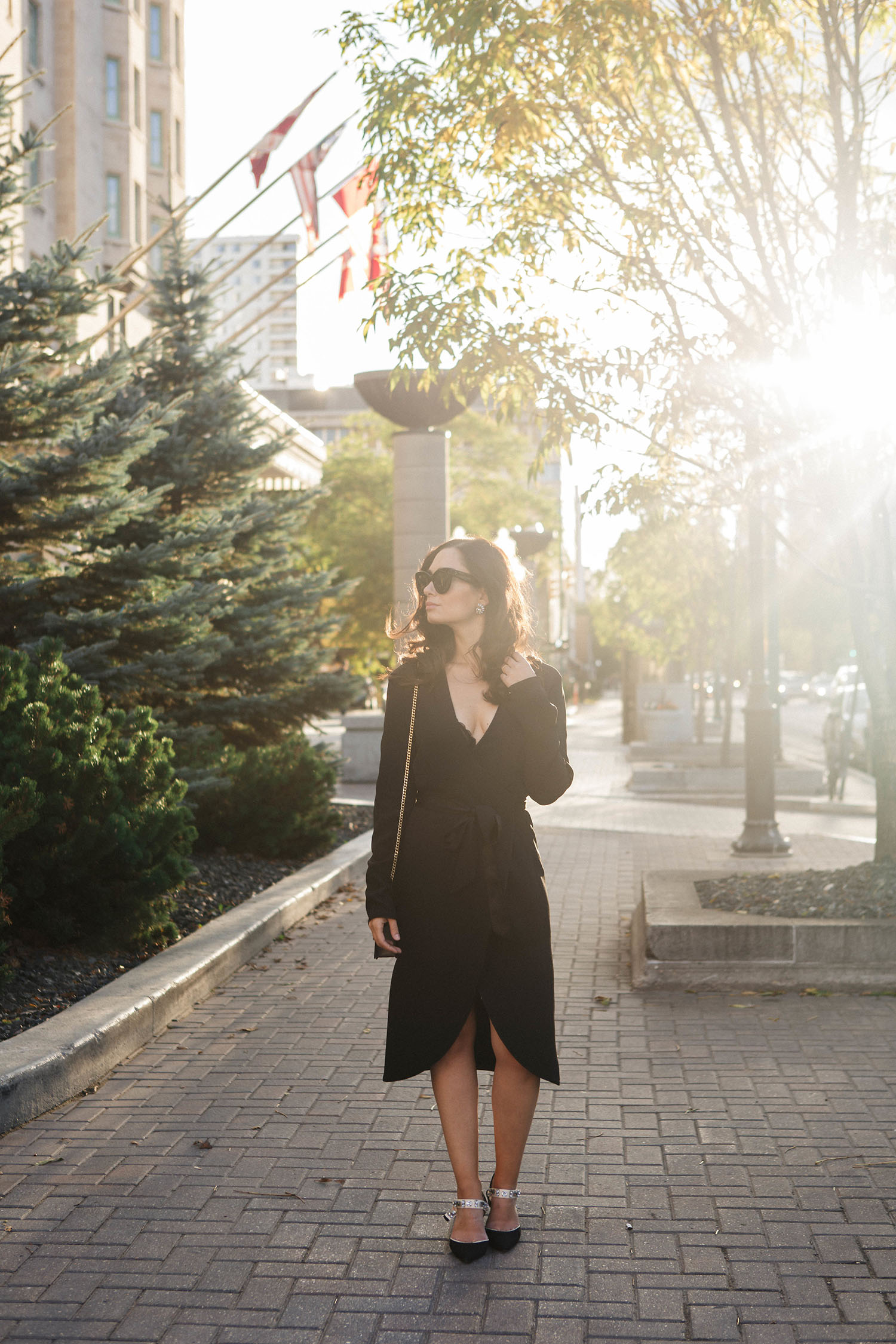 Fashion blogger Cee Fardoe of Coco & Vera stands at the Fort Garry Hotel in Winnipeg wearing a black silk wrap dress and Zara bejewelled slingback pumps, photographed by Christa Wong Photography