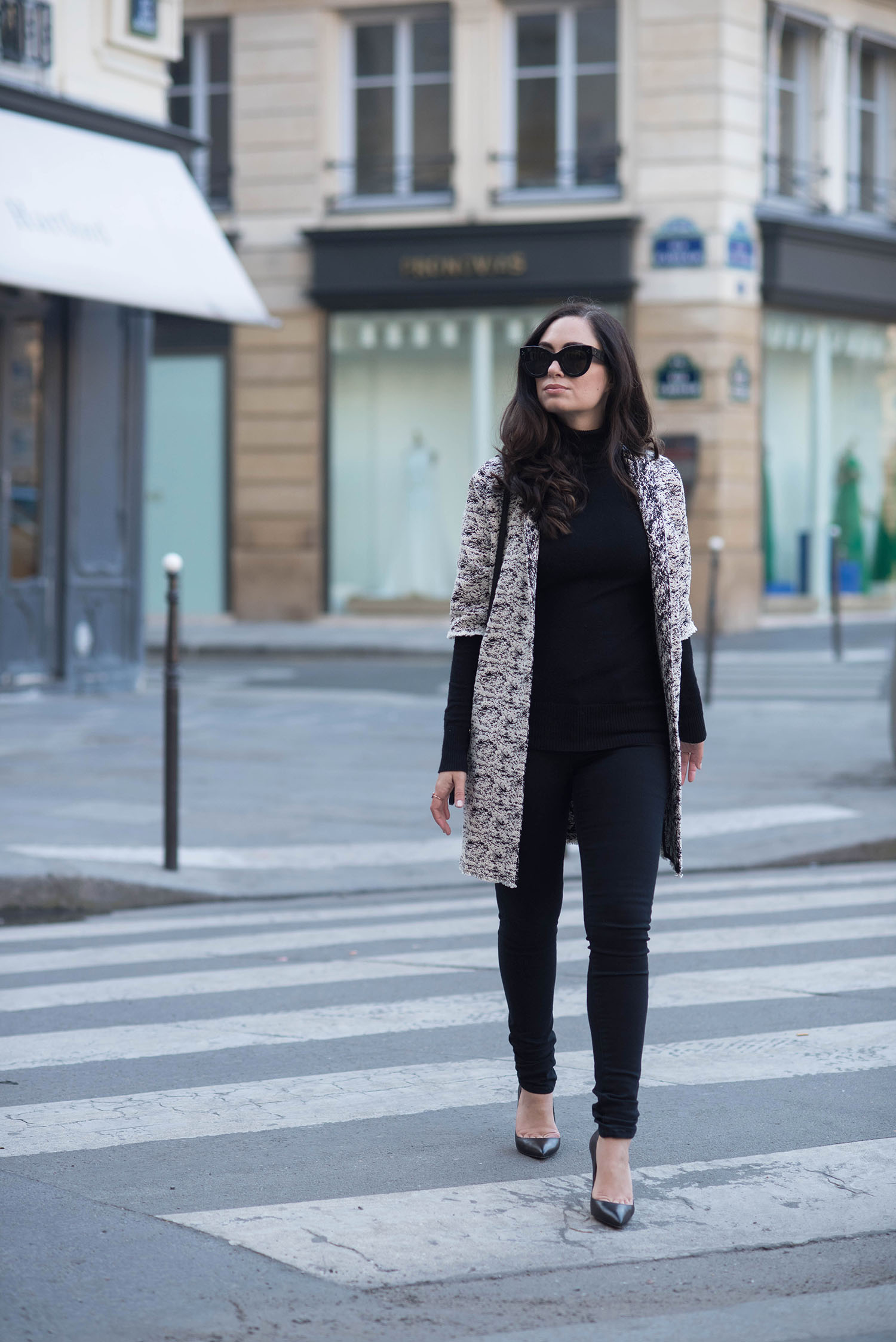 Fashion blogger Cee Fardoe of Coco & Vera walks at Place des Victoires in Paris wearing a Floriane Fosso coat and Christian Louboutin Pigalle pumps