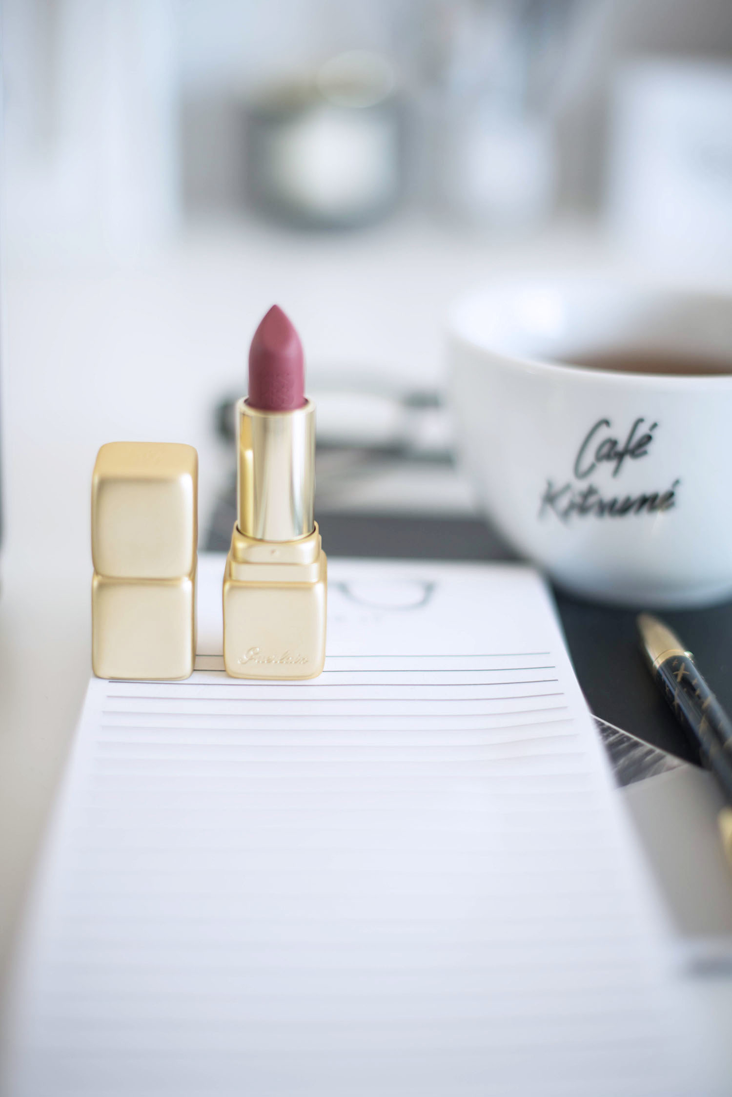 Desk details in the home office of Canadian fashion blogger Cee Fardoe of Coco & Vera, including a gold tube of Guerlain lipstick and a Cafe Kitsune cup