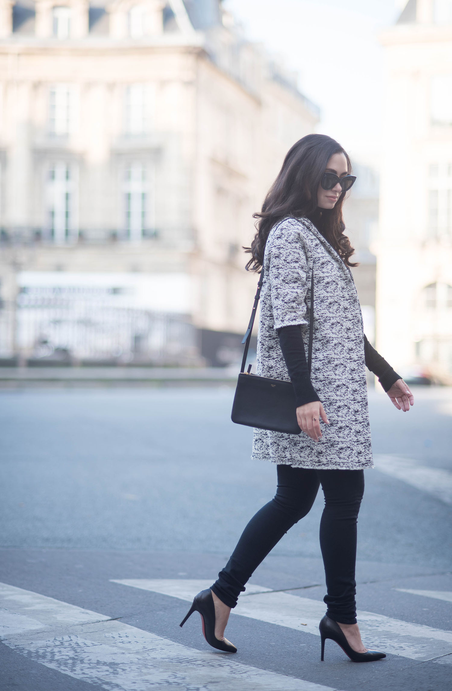 Fashion blogger Cee Fardoe of Coco & Vera crosses the street at Place des Victories in Paris carrying a Celine trio bag and wearing Mavi jeans
