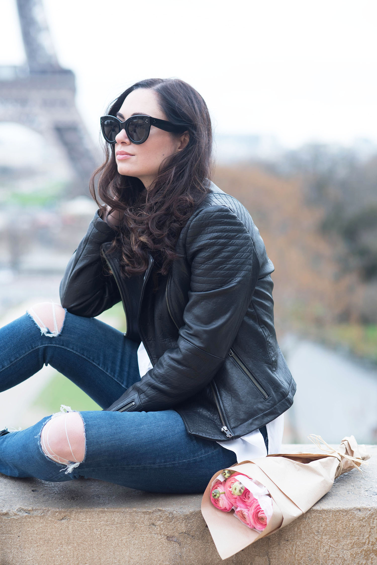 Portrait of Winnipeg fashion blogger Cee Fardoe of Coco & Vera sitting at Place Trocadero wearing a Cupcakes and Cashmere leather jacket with Celine Audrey sunglasses