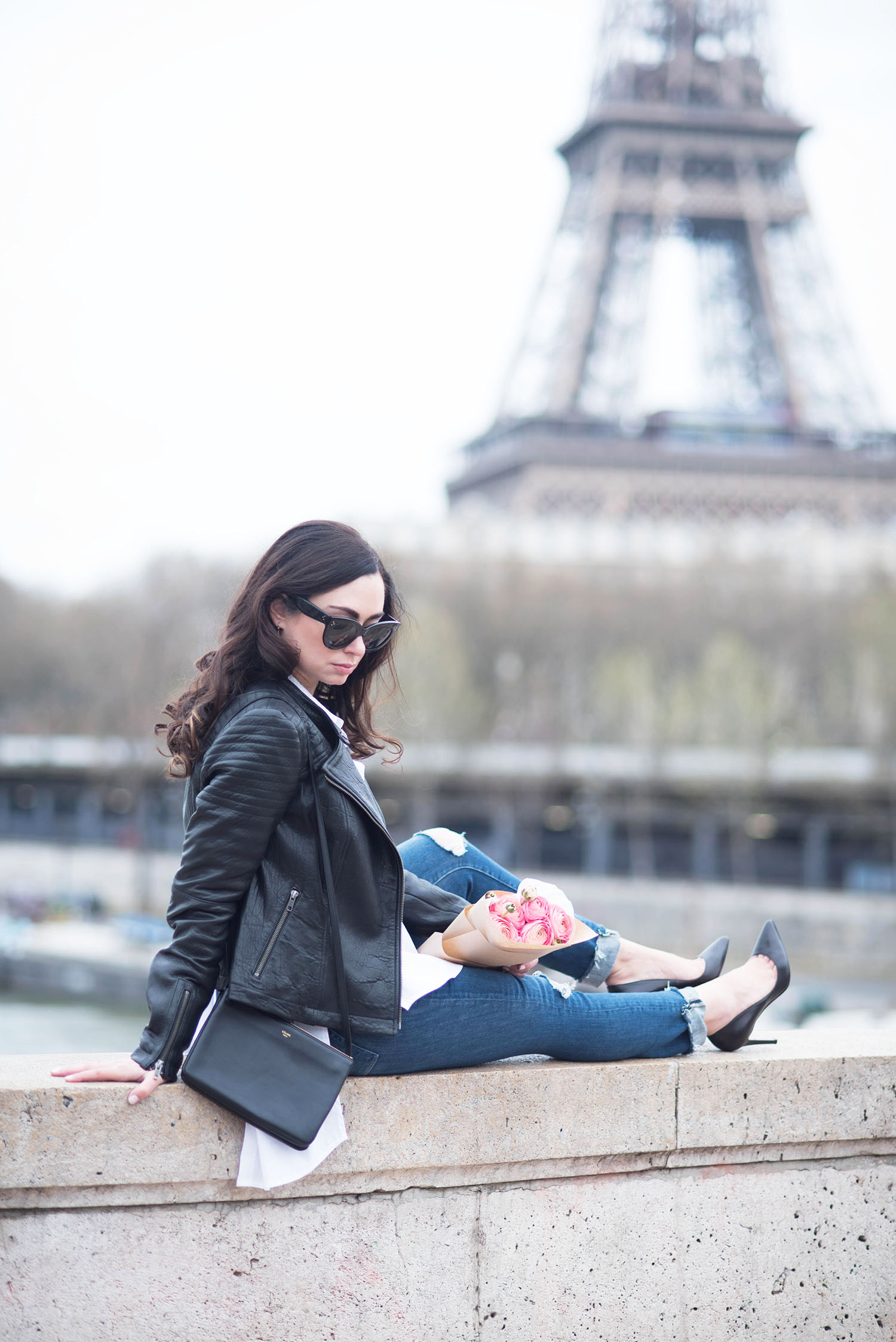 Fashion blogger Cee Fardoe of Coco & Vera sits near the Eiffel Tower in Paris wearing Christian Louboutin Pigalle pumps and Paige Hoxton jeans