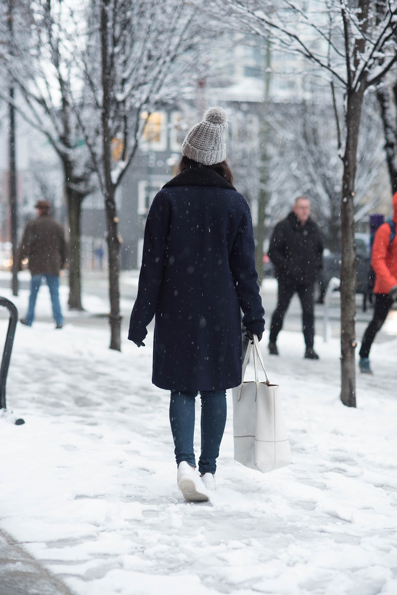 Fashion blogger Cee Fardoe of Coco & Vera wears a Navy coat and Stan Smith sneakers in a snow storm in Vancouver