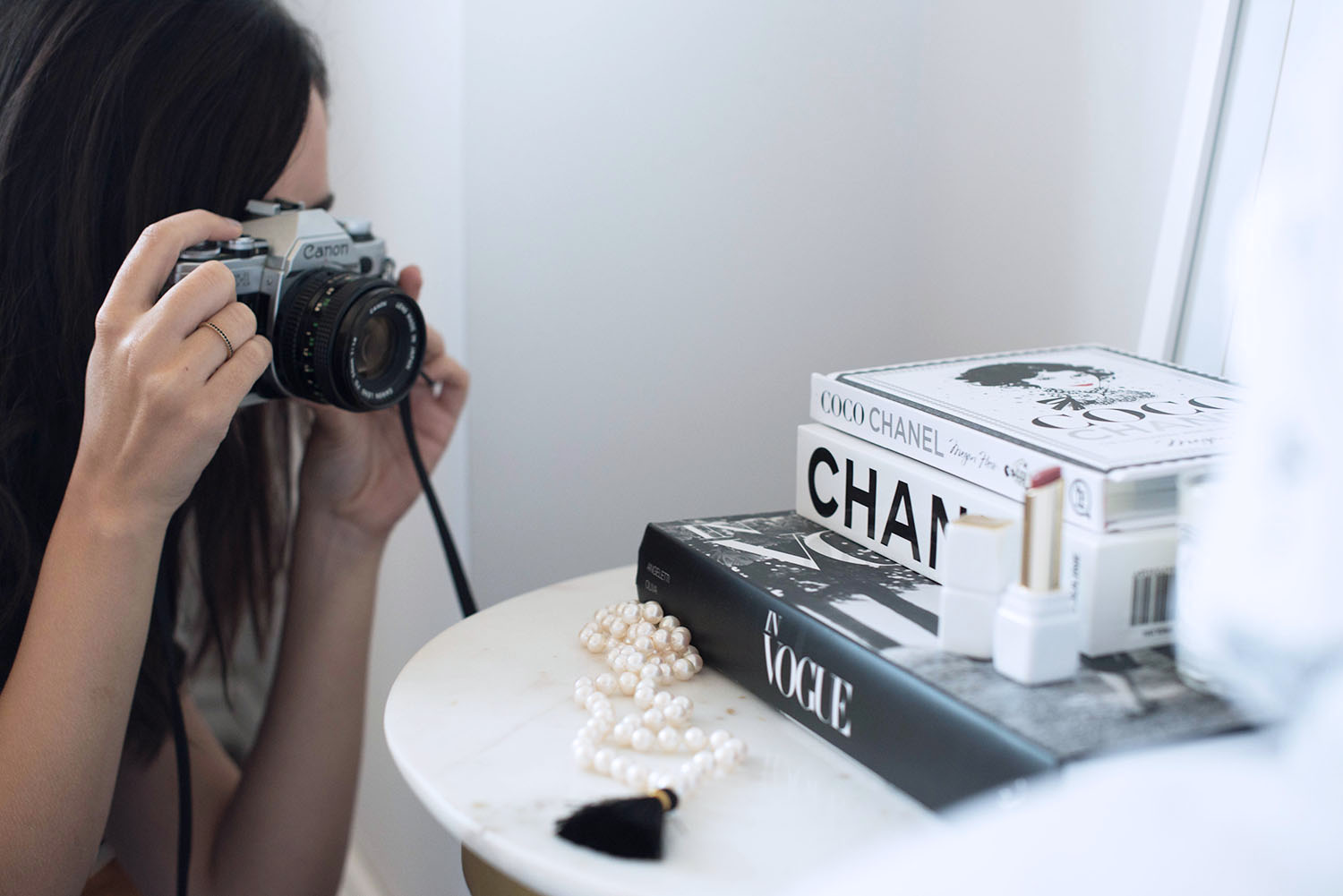 Top Canadian fashion blogger Cee Fardoe of Coco & Vera uses a Canon A1-E camera to take photos of a pile of books on her side table