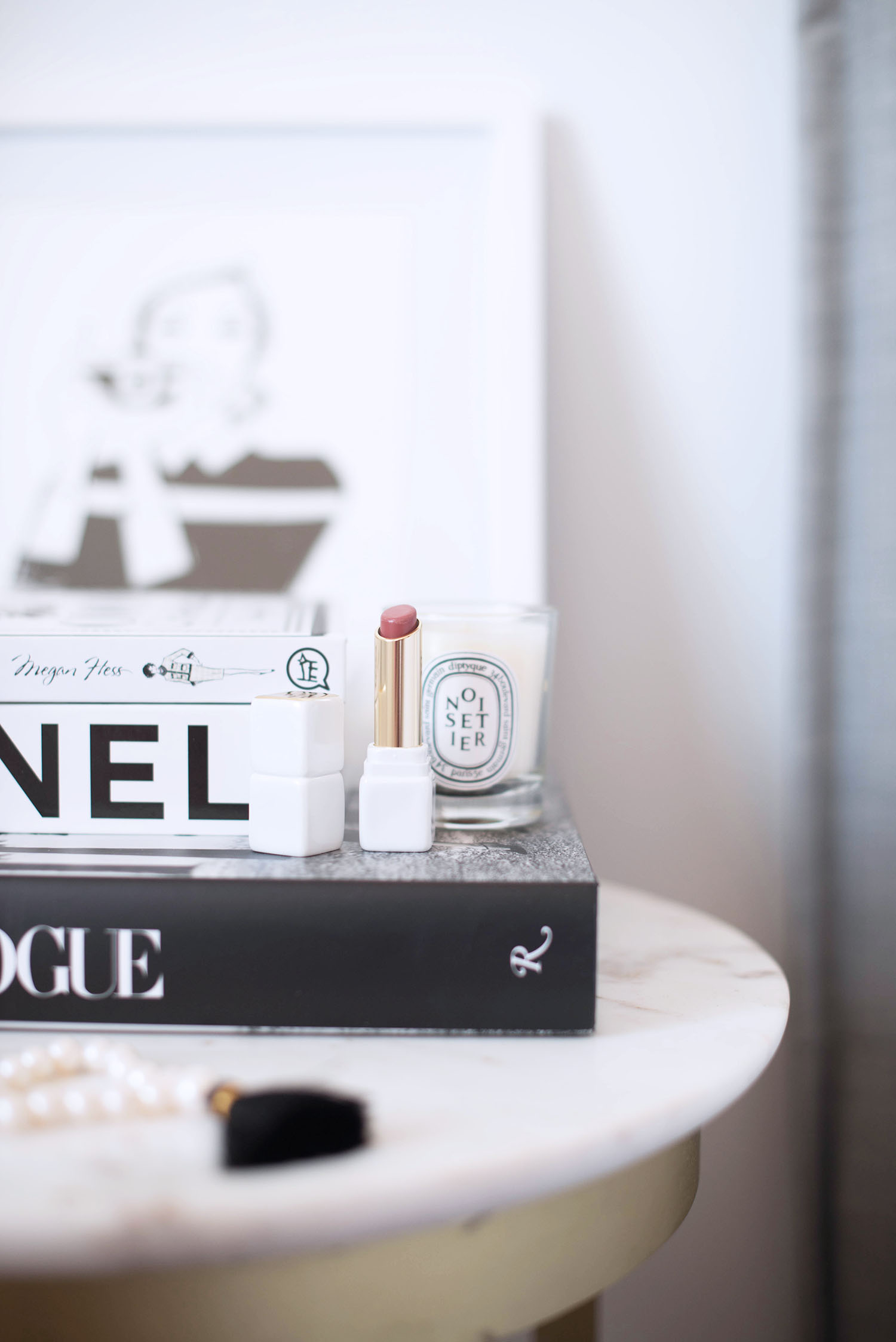 Details on the side table of Winnipeg fashion blogger Cee Fardoe of Coco & Vera, including a Diptyque Noisier candle, Guerlain lipstick and CHANEL book