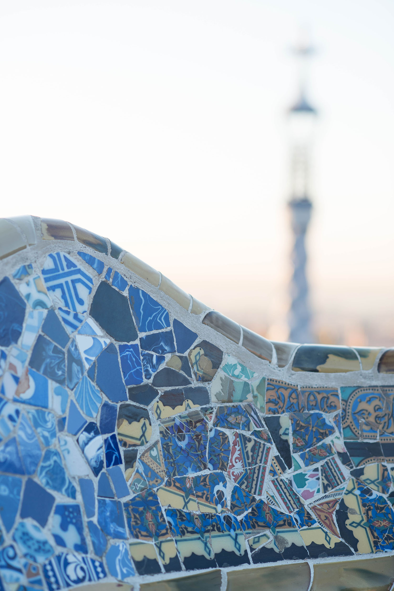 Sunrise over blue mosaic tiles at Antoni Gaudi's Parc Guell in Barcelona, Spain, as photographed by travel blogger Cee Fardoe of Coco & Vera