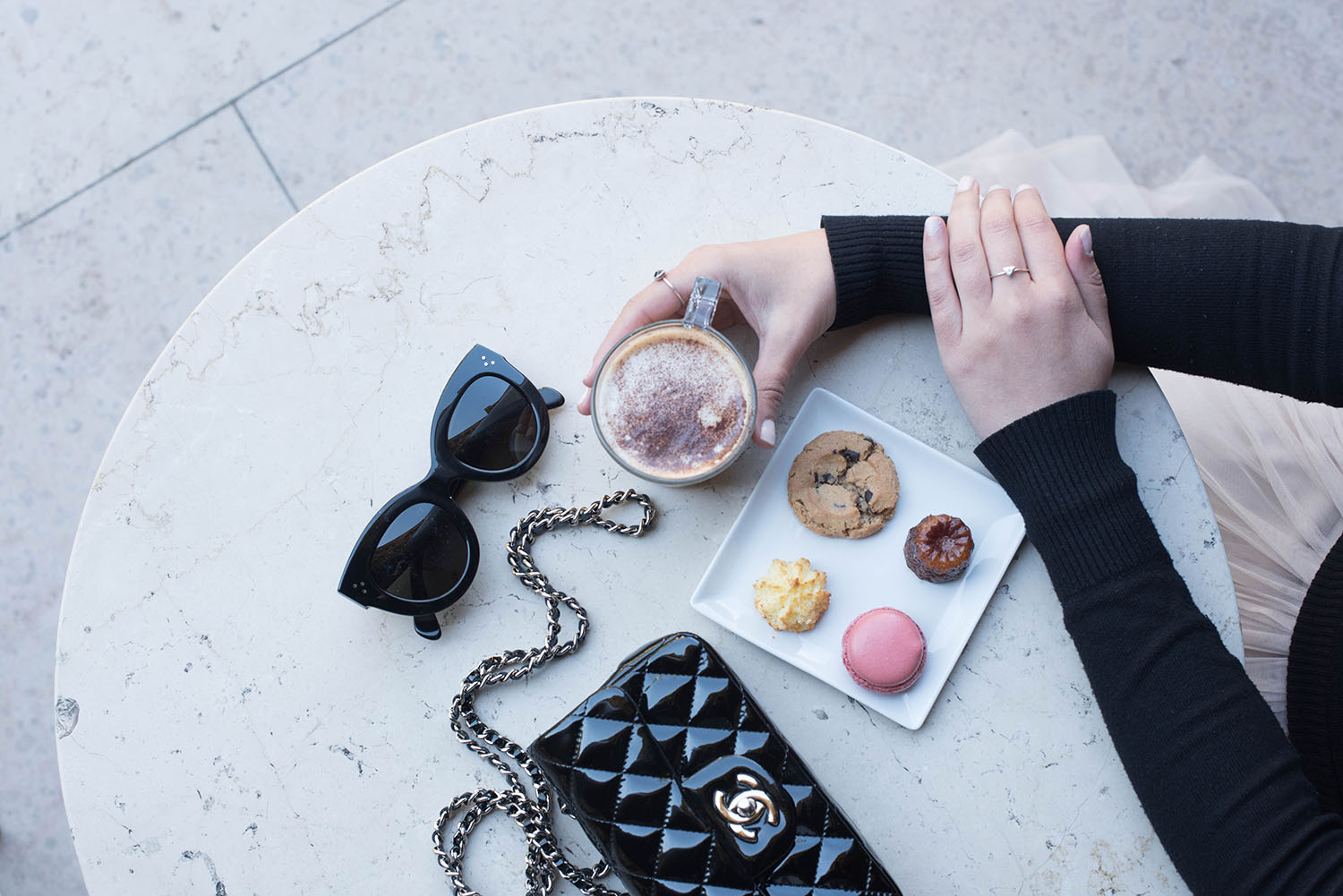 Fashion blogger Cee Fardoe of Coco & Vera enjoys cafe gourmand at the Petit Palais, drinking coffee with her Celine sunglasses and Chanel handbag on the table in front of her