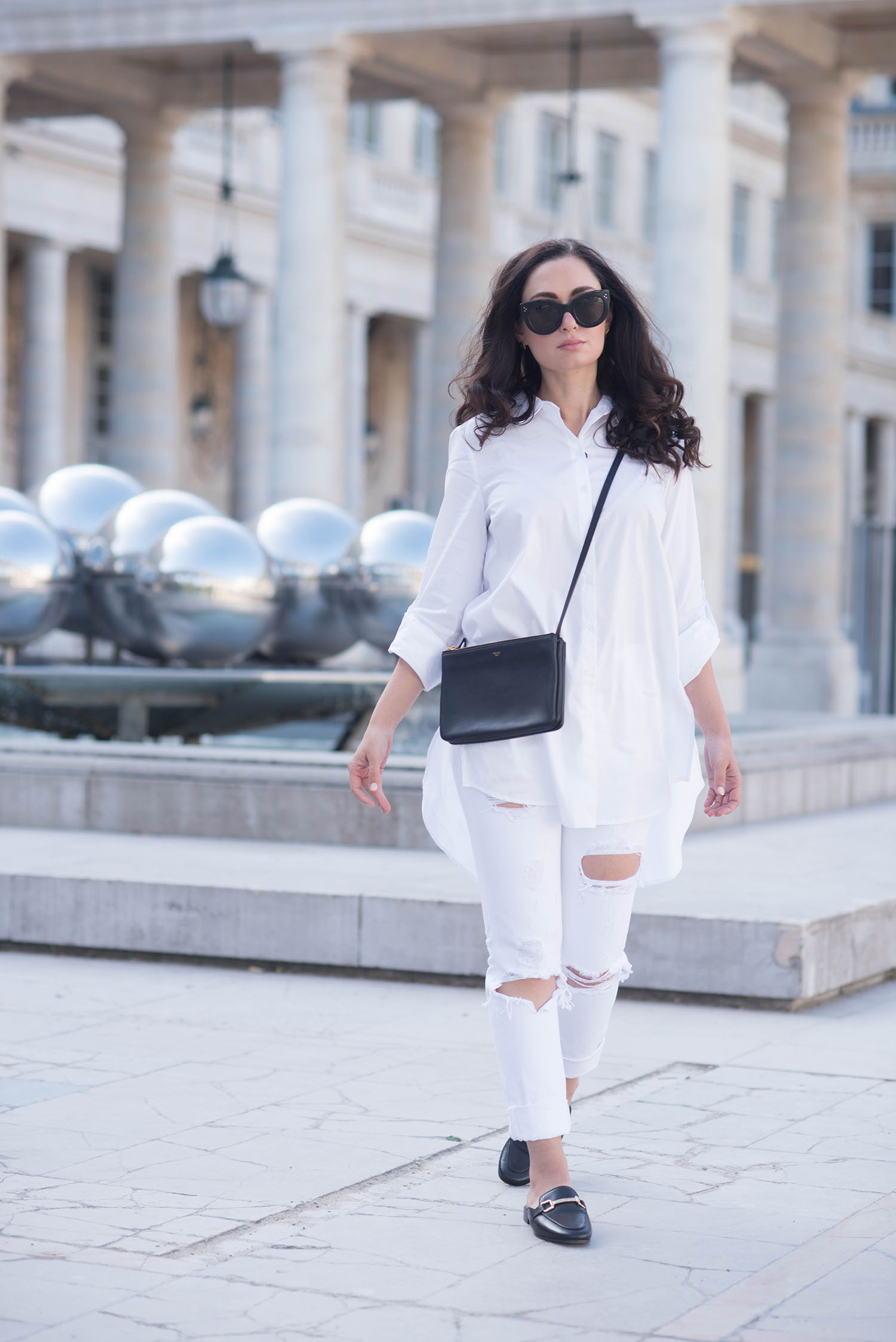 Winnipeg fashion blogger Cee Fardoe of Coco & Vera walks through the Palais Royal in Paris wearing white Grlfrnd Karolina jeans and carrying a Celine trio bag