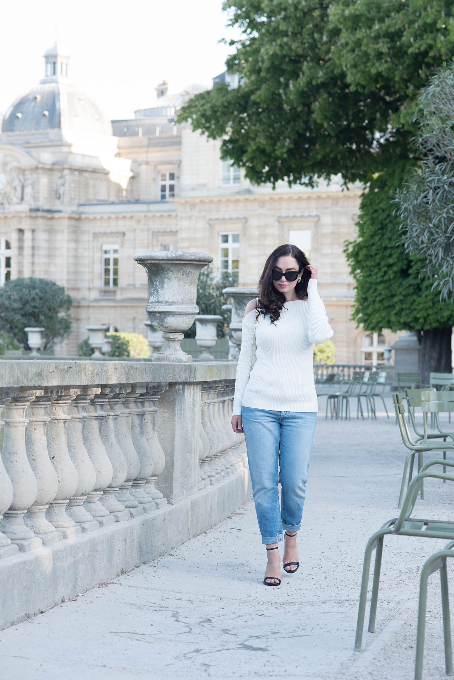 Fashion blogger Cee Fardoe of Coco & Vera walks through the Jardin du Luxembourg in Paris in the spring wearing Zara boyfriend jeans and a Majorelle Twister sweater