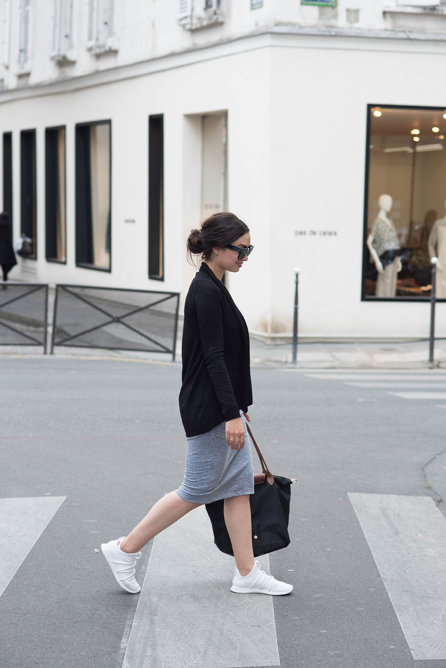 Fashion blogger Cee Fardoe of Coco & Vera walks the streets of Le Marais in Paris wearing Skye Footwear sneakers and a black Zara cardigan