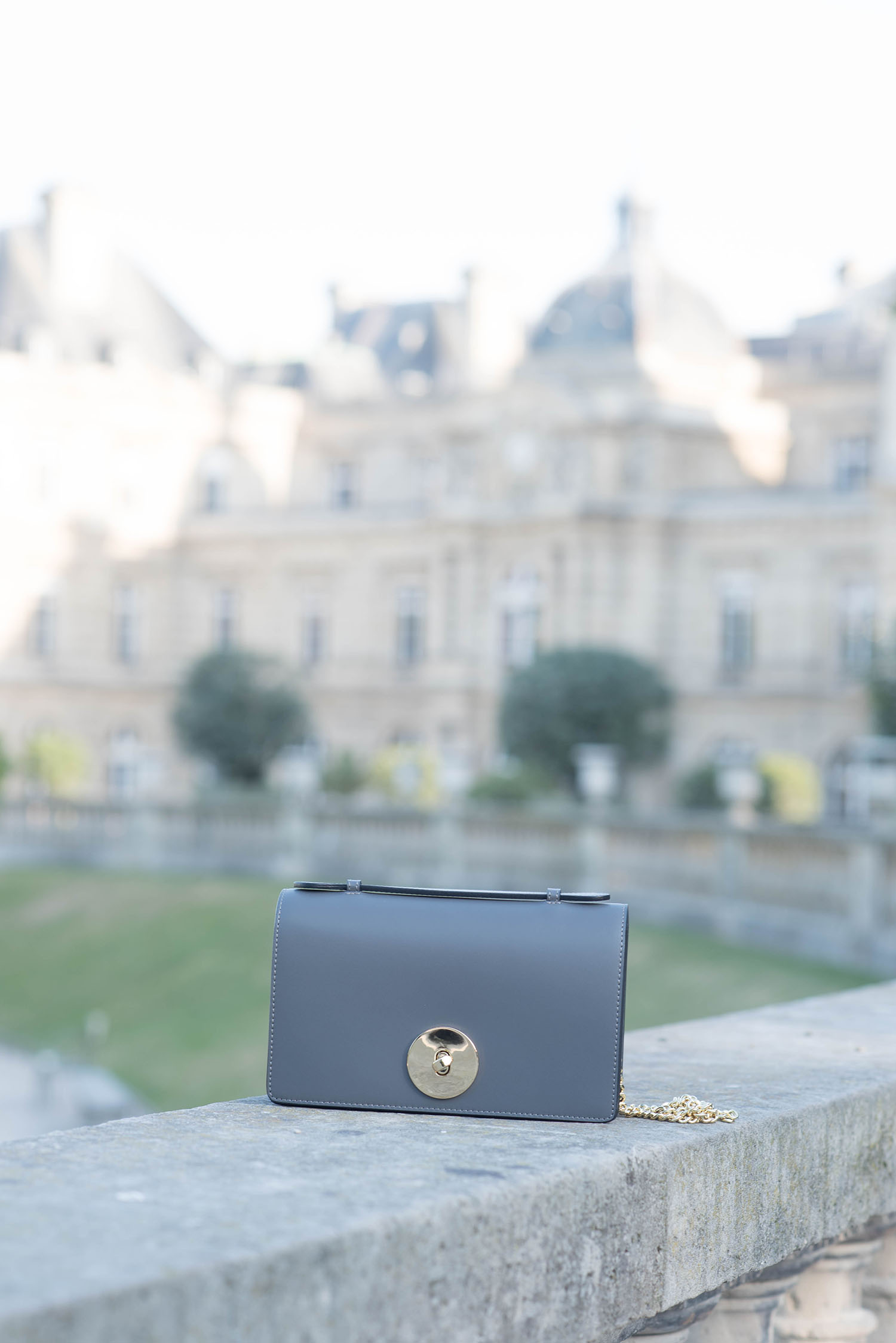 A grey leather Camelia Roma handbag sits on the fence in the Jardin du Luxembourg in Paris, as captured by Canadian fashion blogger Cee Fardoe of Coco & Vera