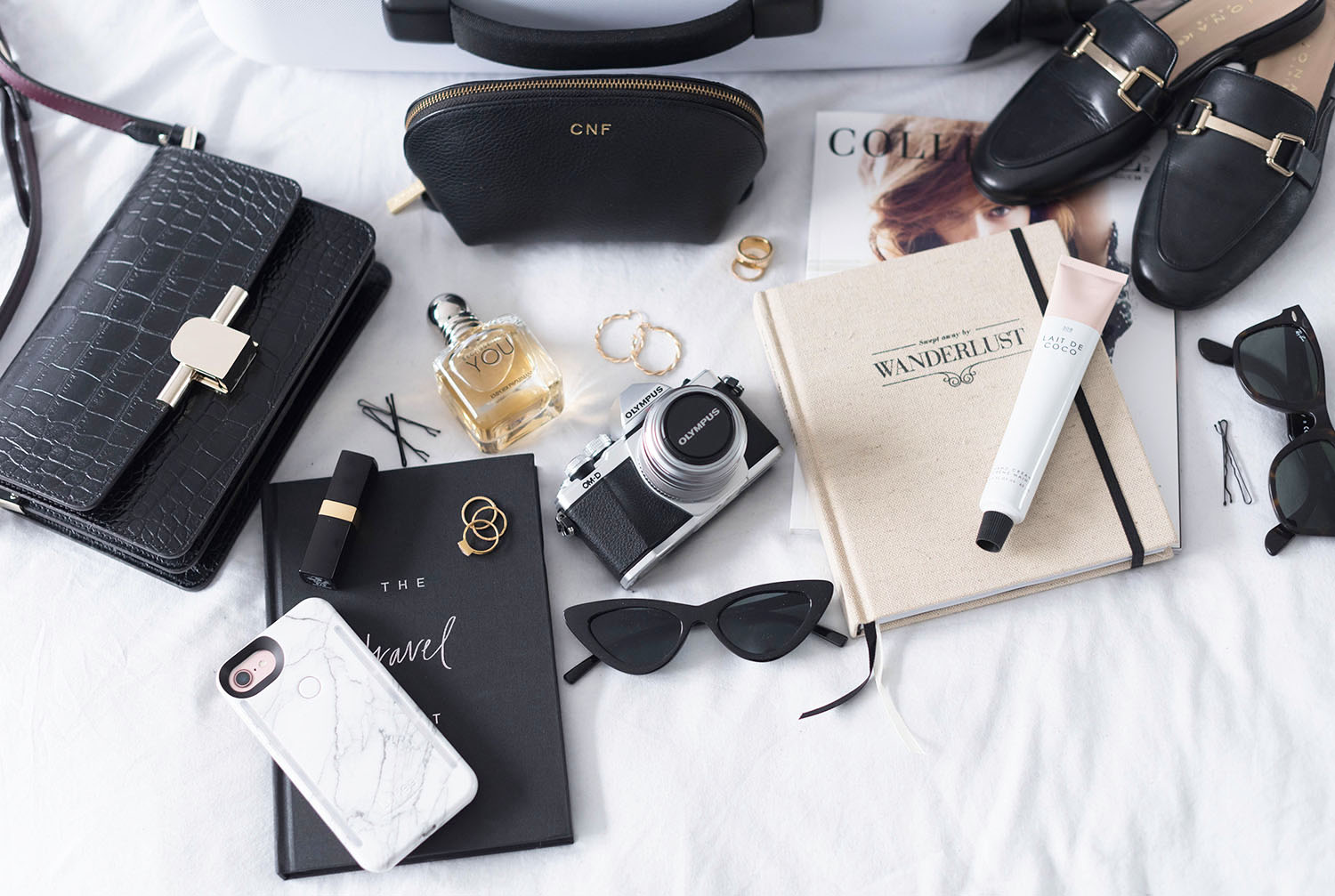 A flatlay of items packed for a trip, including a LuMee phone case and Zara Spec sunglasses, as arranged by Winnipeg fashion blogger Cee Fardoe of Coco & Vera