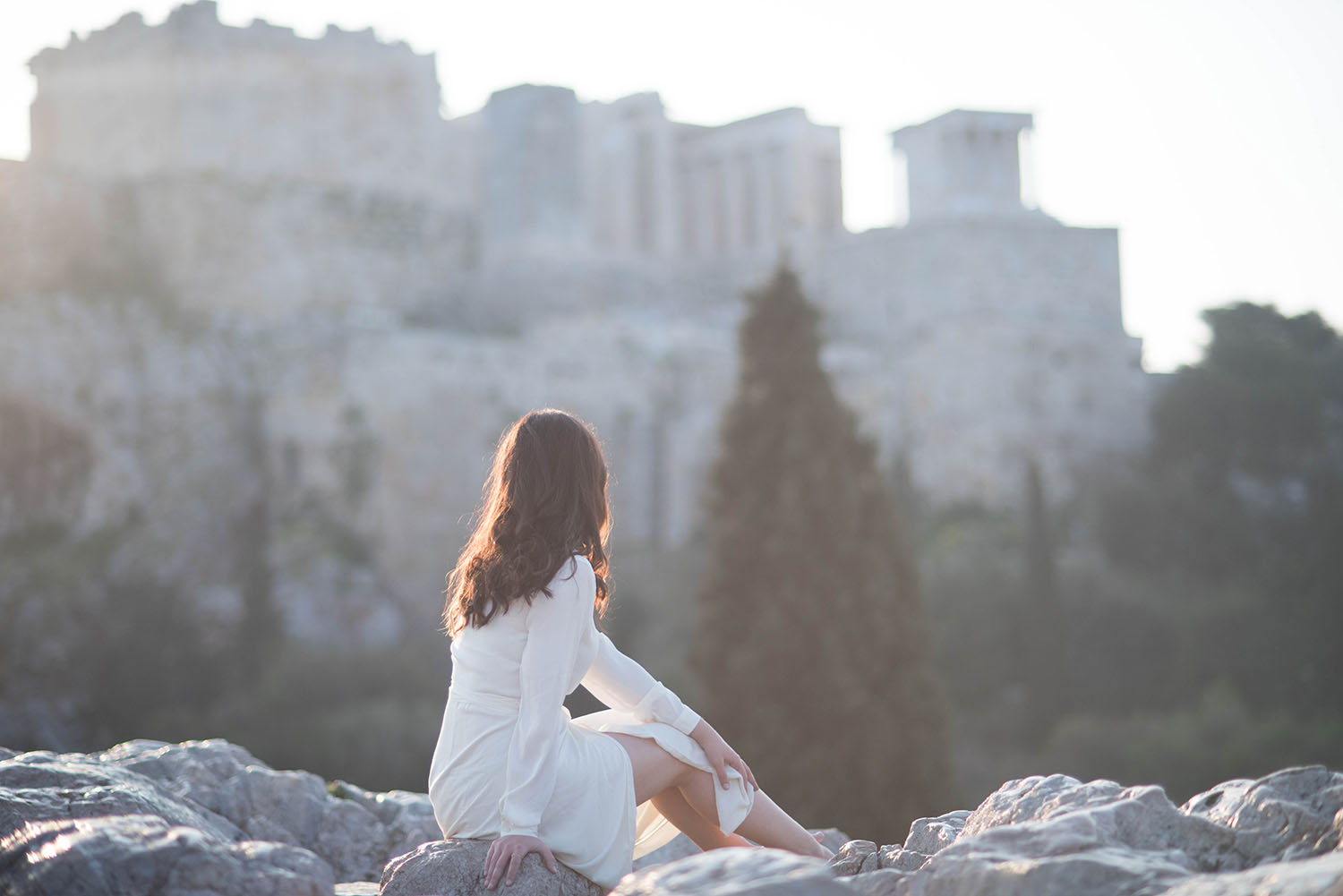 Fashion blogger Cee Fardoe of Coco & Vera sits on a rock near Acropolis Hill in Athens, Greece, wearing a Lovers + Friends white maxi dress