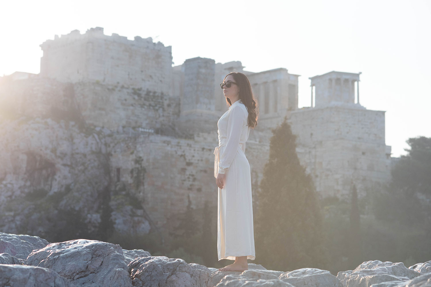 Fashion blogger Cee Fardoe of Coco & Vera stands near Acropolis Hill in Athens, Greece wearing a white Lovers + Friends dress and RayBan Wayfarer sunglasses