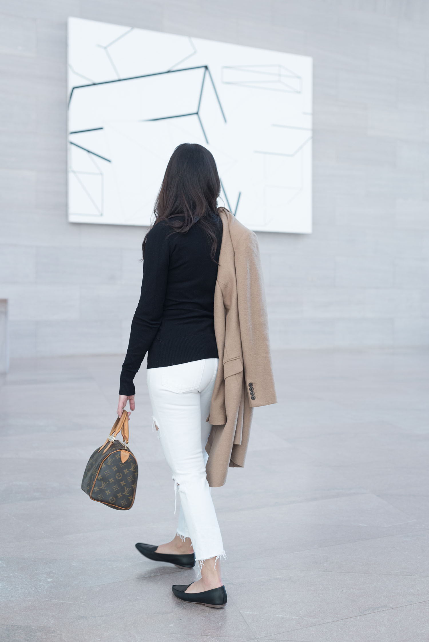 Fashion blogger Cee Fardoe of Coco & Vera walks in the National Gallery of Art in Washington DC wearing a Le Chateau turtleneck sweater and carrying a Louis Vuitton Speedy 25 handbag